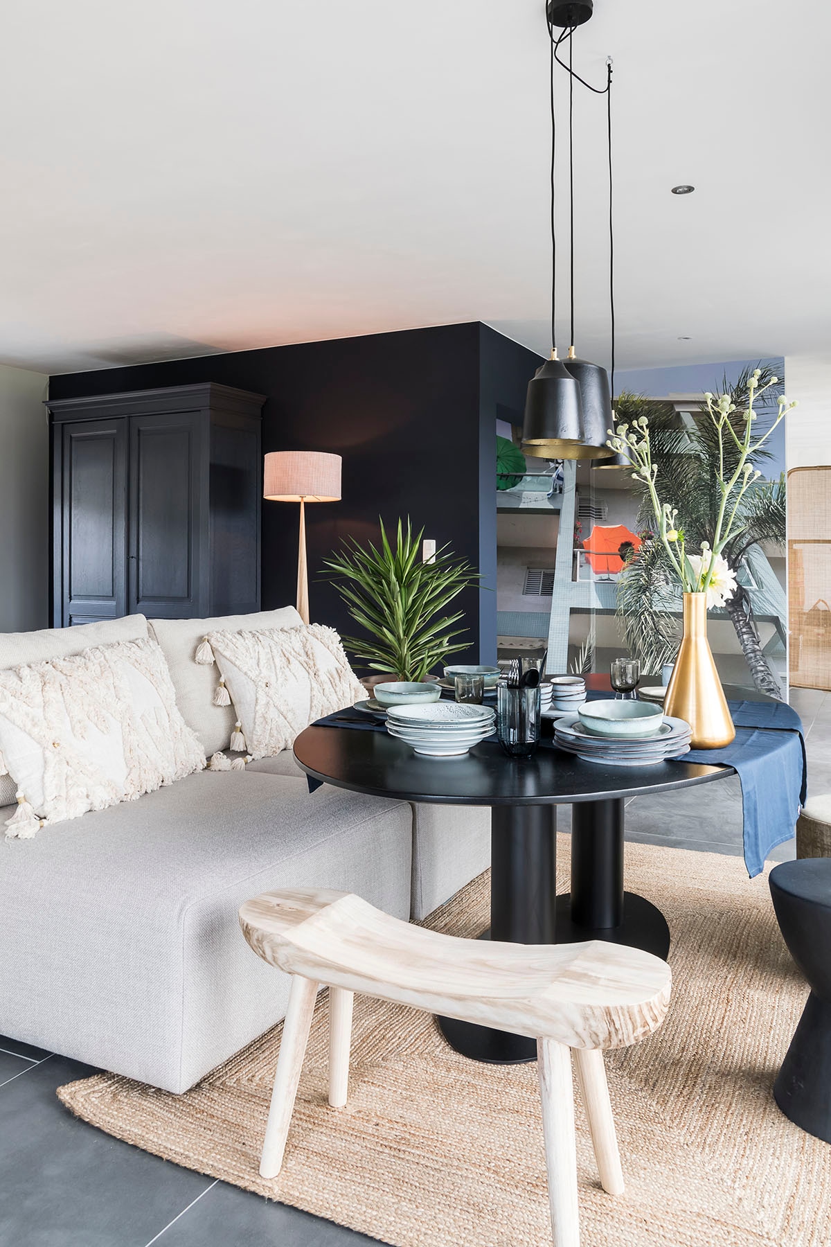 Hanglampen (Lifestyle), poefs Xavio – 2 tegen elkaar (), kussens op poef (Riverdale), tafel Buddha Dining (), kruk (Mica), tapijt (Riverdale), vloerlamp (Lucide).