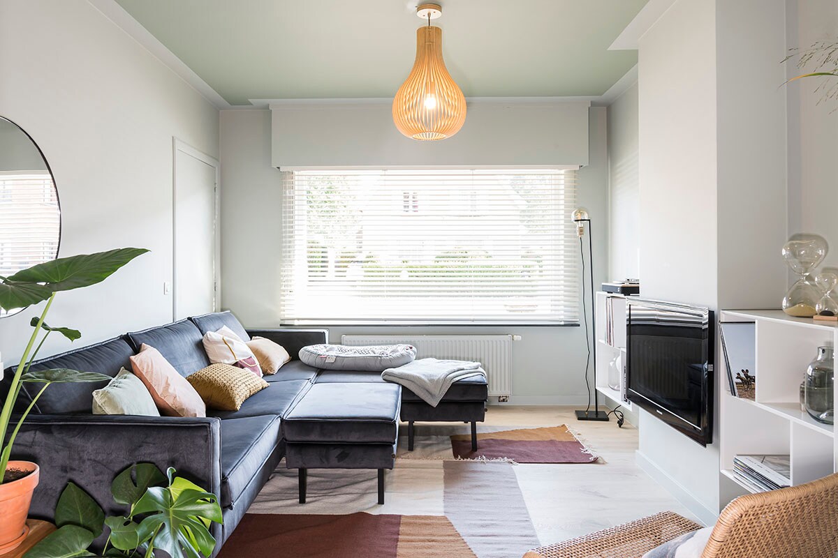 Raamdecoratie: horizontale jaloezieën 50 mm – H9024 (). Zetel en hocker – velvet antraciet (BePureHome), hanglamp en vloerlamp (Lucide), spiegel – rond (HKliving), tapijten (Ferm Living).