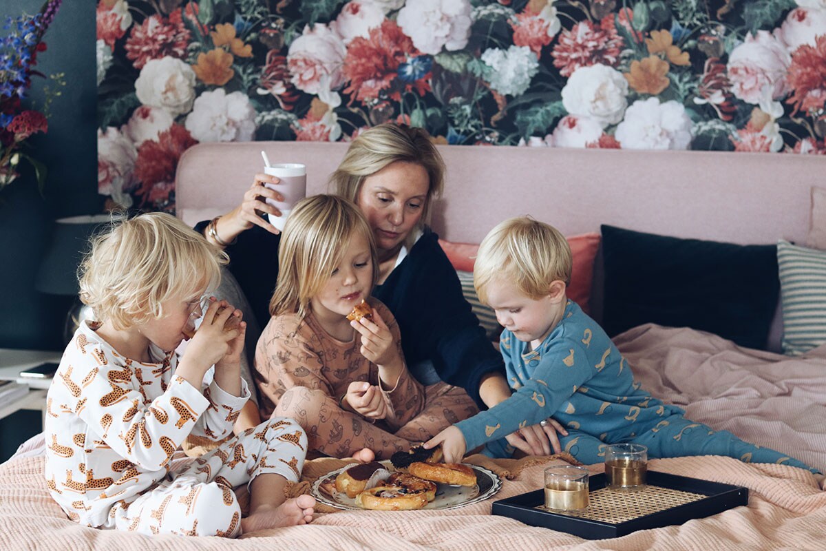 Boxspring Pepper uit de Lifestyle by vtwonen collectie (Swiss Sense), lakens en dienblad (H&amp;M Home), glaasjes (Serax), pyjama’s kinderen (Trixie). Gestreept kussen (IKEA), roze kussen met varenprint (Hema).