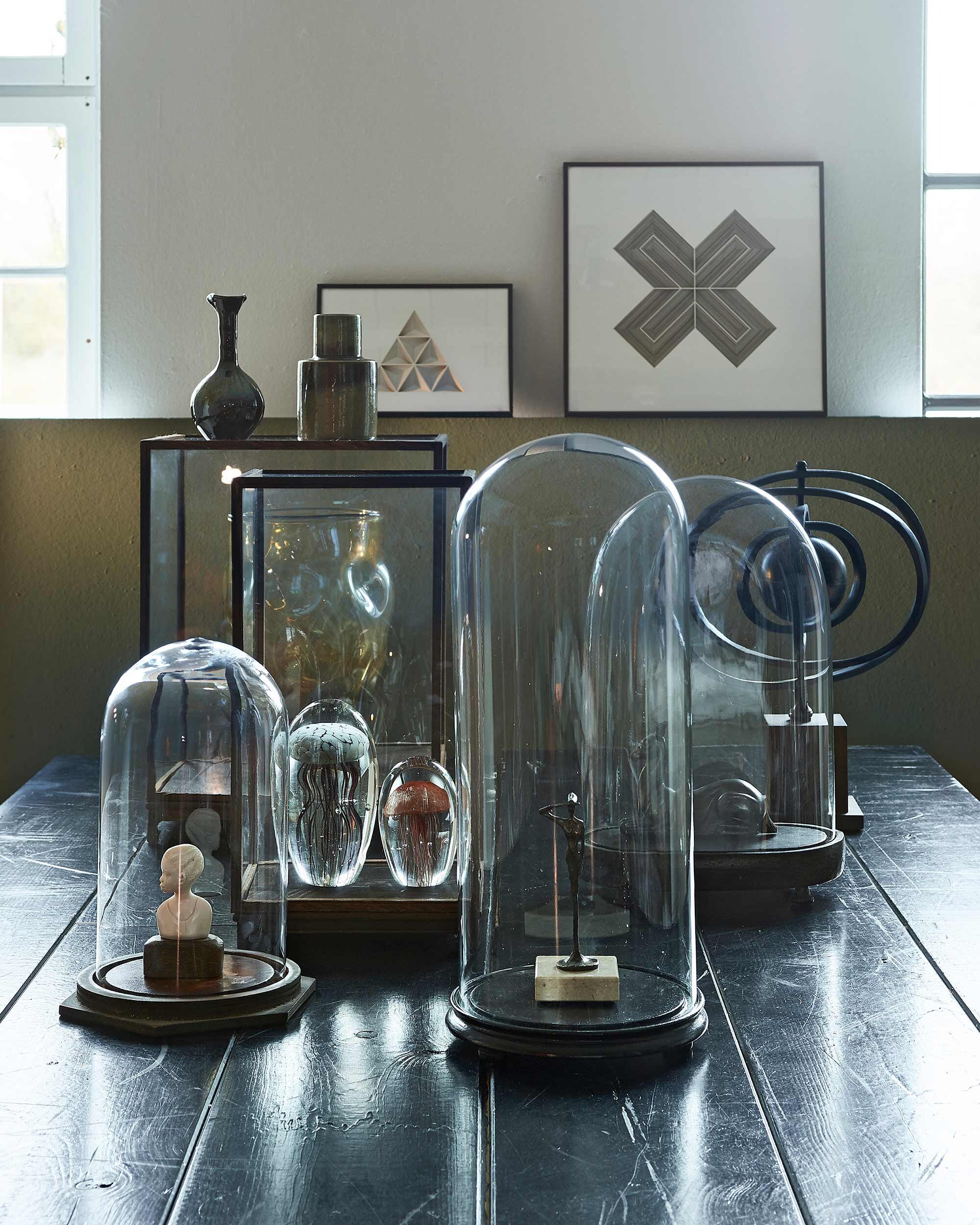 Wand geschilderd met muurverf Classico in kleur Belgian Wilderness (). Rechthoekige en vierkante vitrines, vaas in vitrine (). Oude stolp, hertje (). Glazen presse-papiers (). Wereldbol met metalen ringen (). Op vitrine vaasje rechts (). Vaasje links, grafisch 3D werk aan de muur (). Rest privébezit.