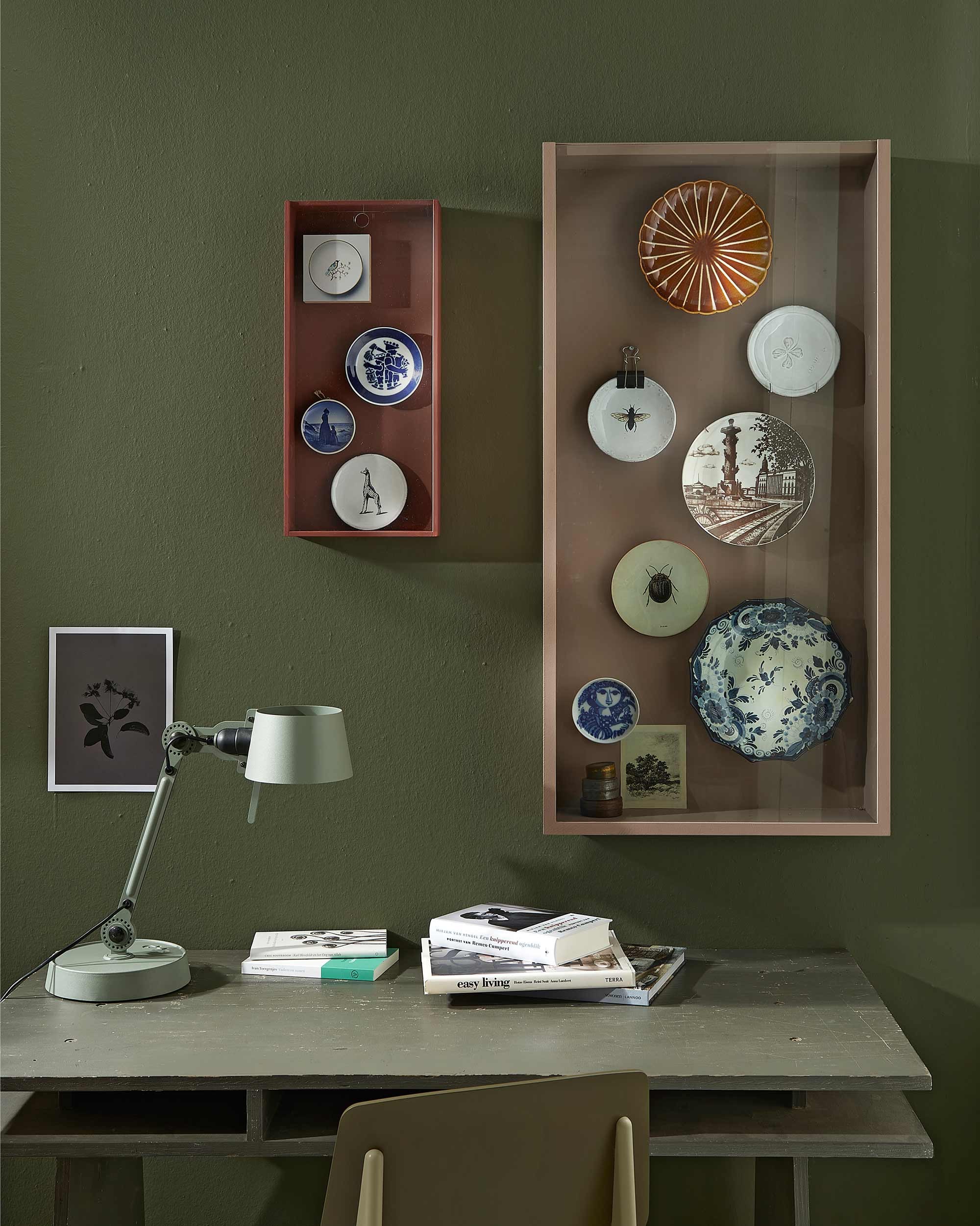 Wand geschilderd met muurverf Classico in kleur Belgian Wilderness. Op maat gemaakt vitrinekastje voor aan de wand (klik voor de werkbeschrijving), geverfd met lakverf in kleur Rose Dust ().Klein vitrinekistje Sammanhang (), geschilderd met lakverf in kleur Cardinal Red () In grote kast: bruin bordje (). Wit bordje klaver, bordje bij (). Bordje kever (). Antiek Japans bord (). Doosjes (weldaad.com). Rest privébezit. Kleine kast: blokje met bordprint (). Bordje giraf (). Rest privébezit. Bureaulamp Tonone, stoel Revolt (). Prent uit . Tafel privébezit.