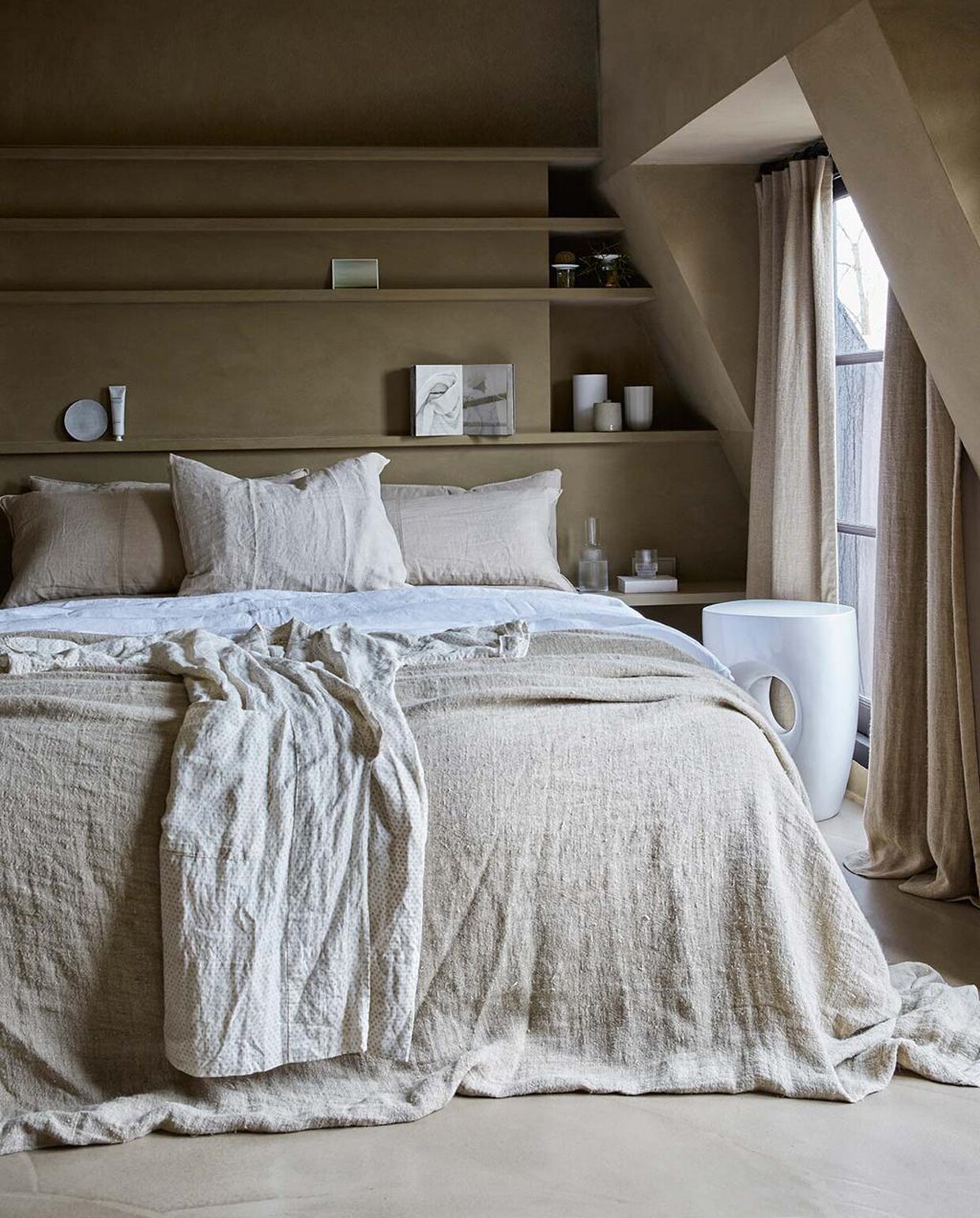 Muurverf Buffalo (Tribe). Vloer (Pureconcept). Witte kruk (Pols Potten). Bedsprei Natural (HKliving). Linnen laken kleur Pure White, voorste kussen kleur Flax (By Mölle). Gordijnen kleur Stonewashed (Chivasso). Waterkan Ripple (Ferm Living). Glazen Ripple van Ferm Living set van 4, voetencrème van Meraki, taupe vaas van D&amp;M Depot, paper vaas van Hay, witte vaas van Menu (vtwonen.nl). Bord van Frédérick Gautier (Serax). Kaart (artlimited.net). Boek Out of Fashion (Birgitta de Vos). Plantjes (Sprout). Kimono (Sukha Amsterdam). Op maat gemaakte kast en kussens privébezit.