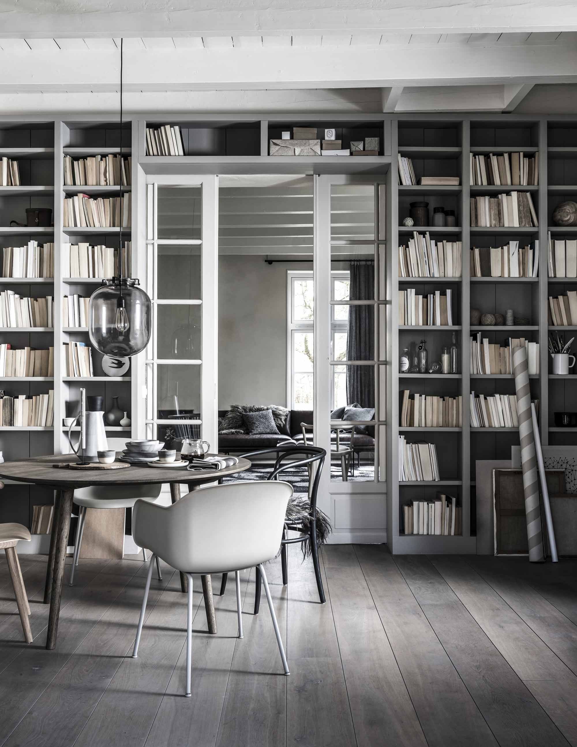 Ronde eettafel . Lichtgrijze kuipstoel en blankhouten stoel . Zwarte eetkamerstoel van Thonet . Schapenvacht op stoel . Grijze glazen hanglamp . Op tafel: zwarte metalen kandelaar, set van 2 , grijze kan en stapel servies , donkergrijze mokken van keramiek met witte rand, donkergrijs bord van keramiek met witte rand en houten bord , glazen koffiepot . In kast: lichtgrijze porseleinen kom met sojawas , zwarte vaas , grijs bolvaasje en wit bolvaasje . Overig zie foto linksboven en privébezit.