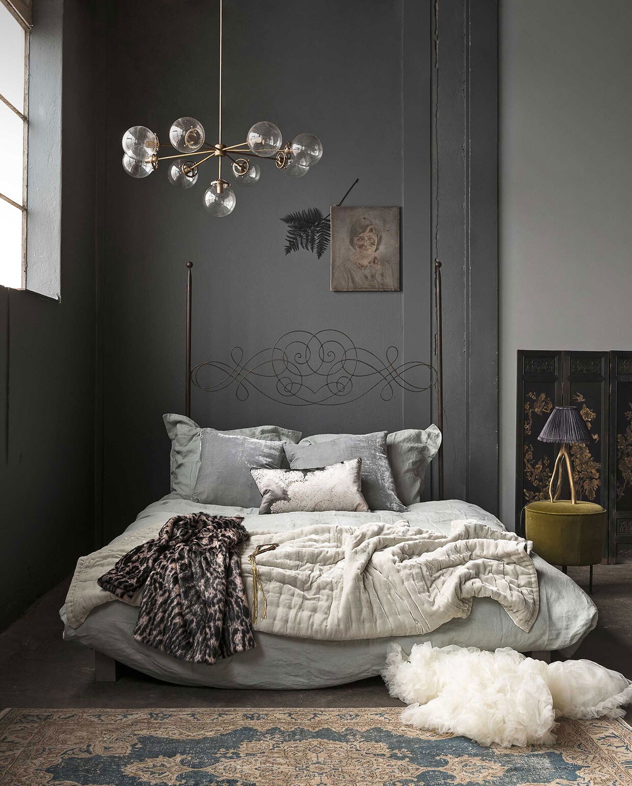 Op de muur muurverf kleur Scree van Little Greene, muurverf kleur Urban Grey van Little Greene (). Bedombouw van staal met hoog gekruld bedhoofdeind (). Linnen dekbedovertrek St. Remy inclusief twee kussenhoezen (). Kussens van zijdefluweel, groene bedsprei van zijdefluweel (). Kussen met print (). Messing kroonluchter met glazen bollen (). Schilderij meisje (). Gedroogde groenzwarte varentak (). Vloerkleed (). Drieluik kamerscherm (). Driepotige lamp met kap (). Mosgroene poef van Gubi (). Jas met dierenprint (). Petticoat (). Gouden ketting ().