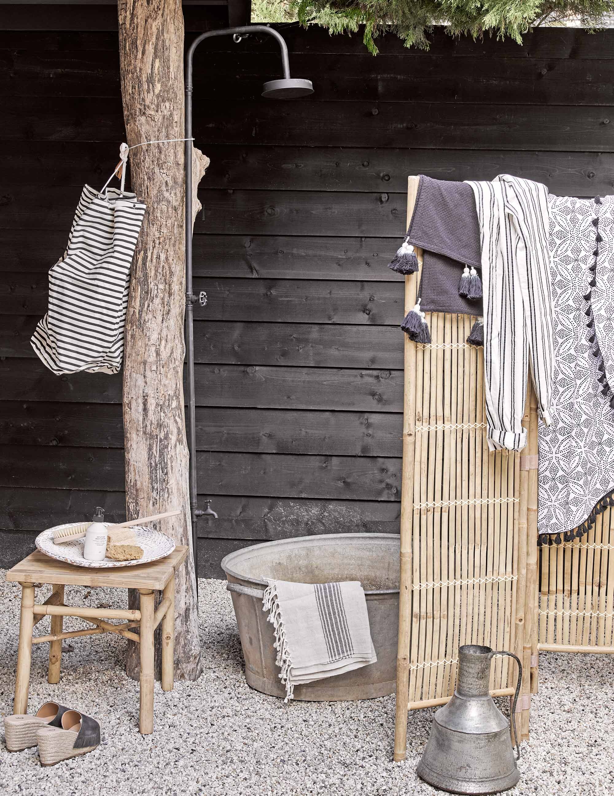 Buitendouche van Bloomingville, gestreepte plunjezak (). Zinken teil (). Slippers (). Gestreepte broek (). Zand-kleurige hamamdoek (). Witte schaal (). Ronde zwart-witte handdoek (). Zilveren kan (). Zwarte doek met kwastjes (). Overig privébezit.,