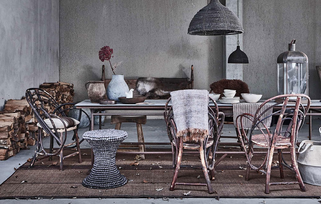 Kastanjehouten stoelen, aardewerken potten, vaas van Imperfettolab, kruk Beaded, zinken tafel, houten krukje uit Azië, hanglampen Beaded Dawn, lantaarn, vloerkleed, plaid, wit servies (). Rendierenvacht (). Kussen met streep, tafelloper (). Bruine schapenvacht, ronde platte schaal, metalen bruine schaal (). Canvas mand ().