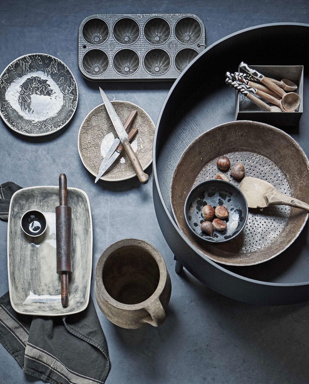 Aardewerken pot, rechthoekig bord van Wonki Ware, ronde borden van Wonki Ware (). Lepels uit Kenia (). Metalen zeef (). Ronde salontafel (). Bakvorm (). Messen klein, groot (). Deegroller (). Zwart schaaltje zwart (). Vierkant bakje van zink (). Platte lepel/spatel ().