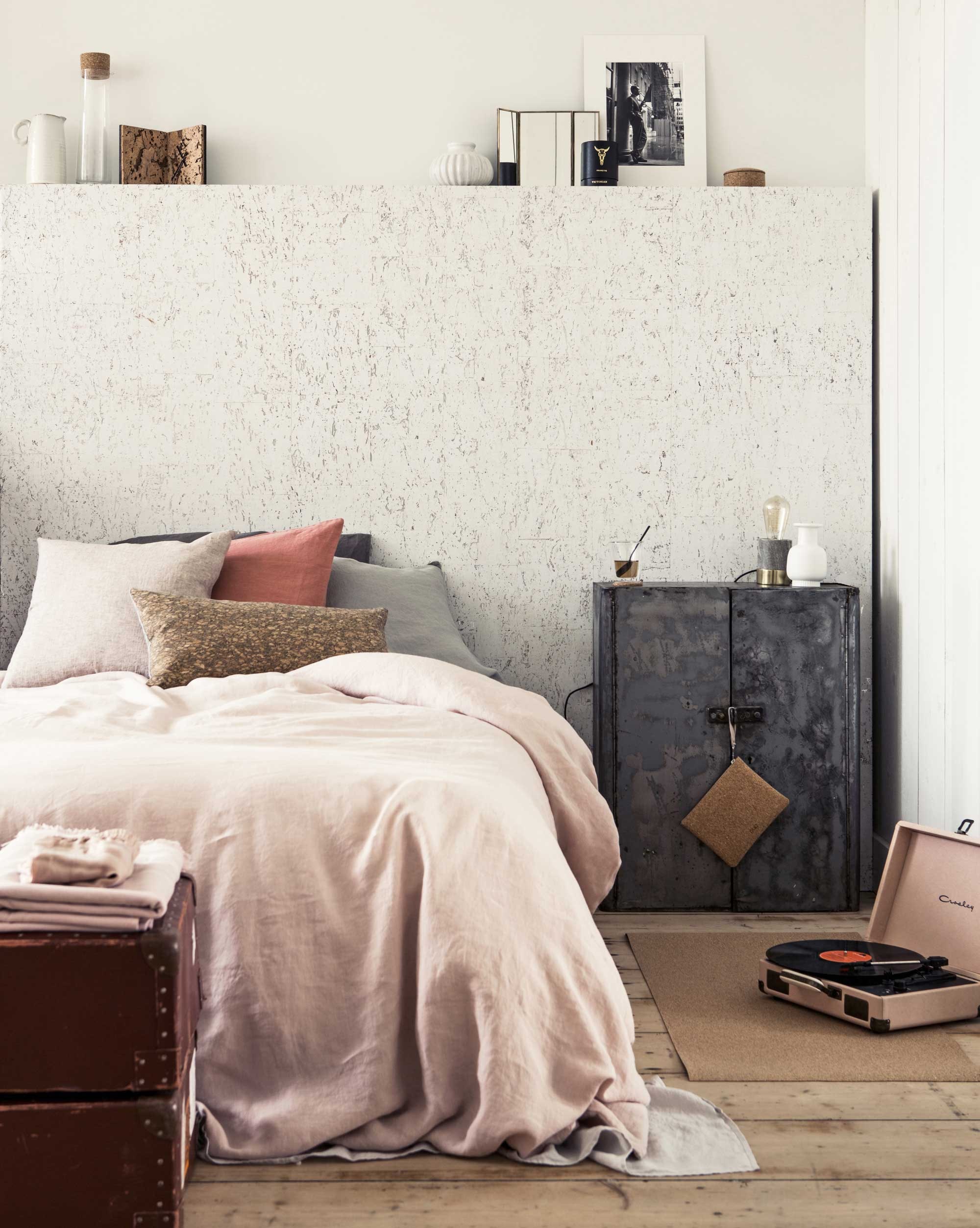 Op de achterwand bij het bed zit kurkbehang Eclat RM63194 (). Dekbedhoes van linnen in de kleur nude, laken van linnen in de kleur chalk, kussenslopen in de kleur peach en light grey (). Pink Salt van By Mölle (The Manor). met gecoat linnen voorkant (Mrs.Me). Kast ().  Journey van kurk (Pucbag). Lamp van marmer, short, klok, spiegeltje, kaars in doosje, fotoprint (). Wit vaasje, witte kan, wit bolvaasje (). Glas met onderzetter van kurk (). Hamamdoek (). Oude filmdozen (). Karaf van glas met kurk van Menu (). van kurk van Hay (MisterDesign).  (Urban Outfitters).