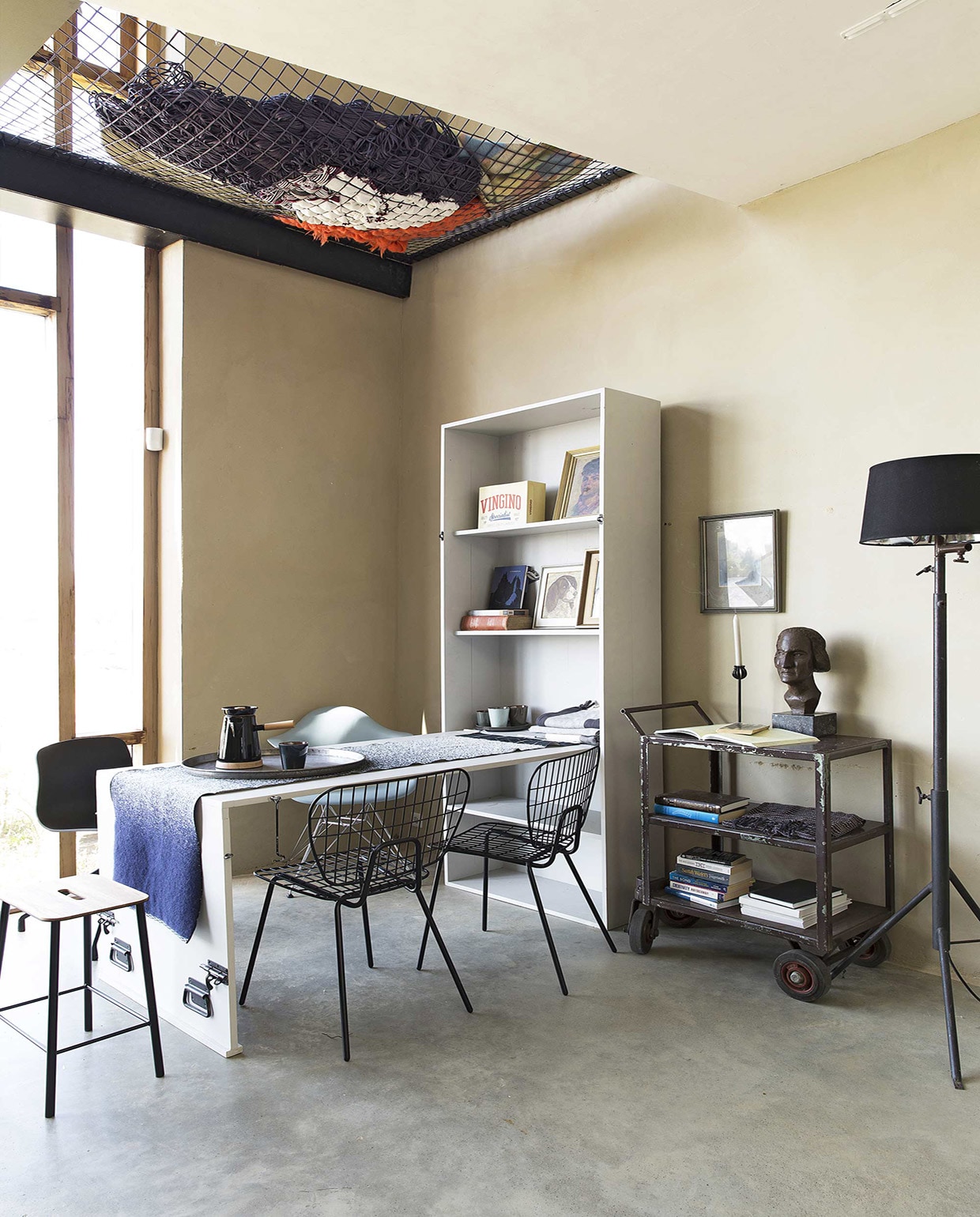 Vloer van gevlinderd beton per m² prijs op aanvraag (House of Bouw). Kast met uitklaptafel (Combitex). Krukje Adam Stool, stoel WM String Chair van Menu, stoel About a Chair AAC10 van Hay kunststof zwart (The Frozen Fountain). Stoel DAR van Eames (Design 020). Tafelloper MOD van Mae Engelgeer, Cowboy Coffee Kettle van Umbra Shift (Restored). Donkerblauwe beker, borden, bekers (Store Without a Home). Dienblad, doeken, hanglamp Cradle Bottle, kaarsenstandaard (Raw Materials). Staande metalen schemerlamp Black Hole Light (Nicky Zwaan). Metalen vintage trolley, buste (Neef Louis). Overig privébezit.