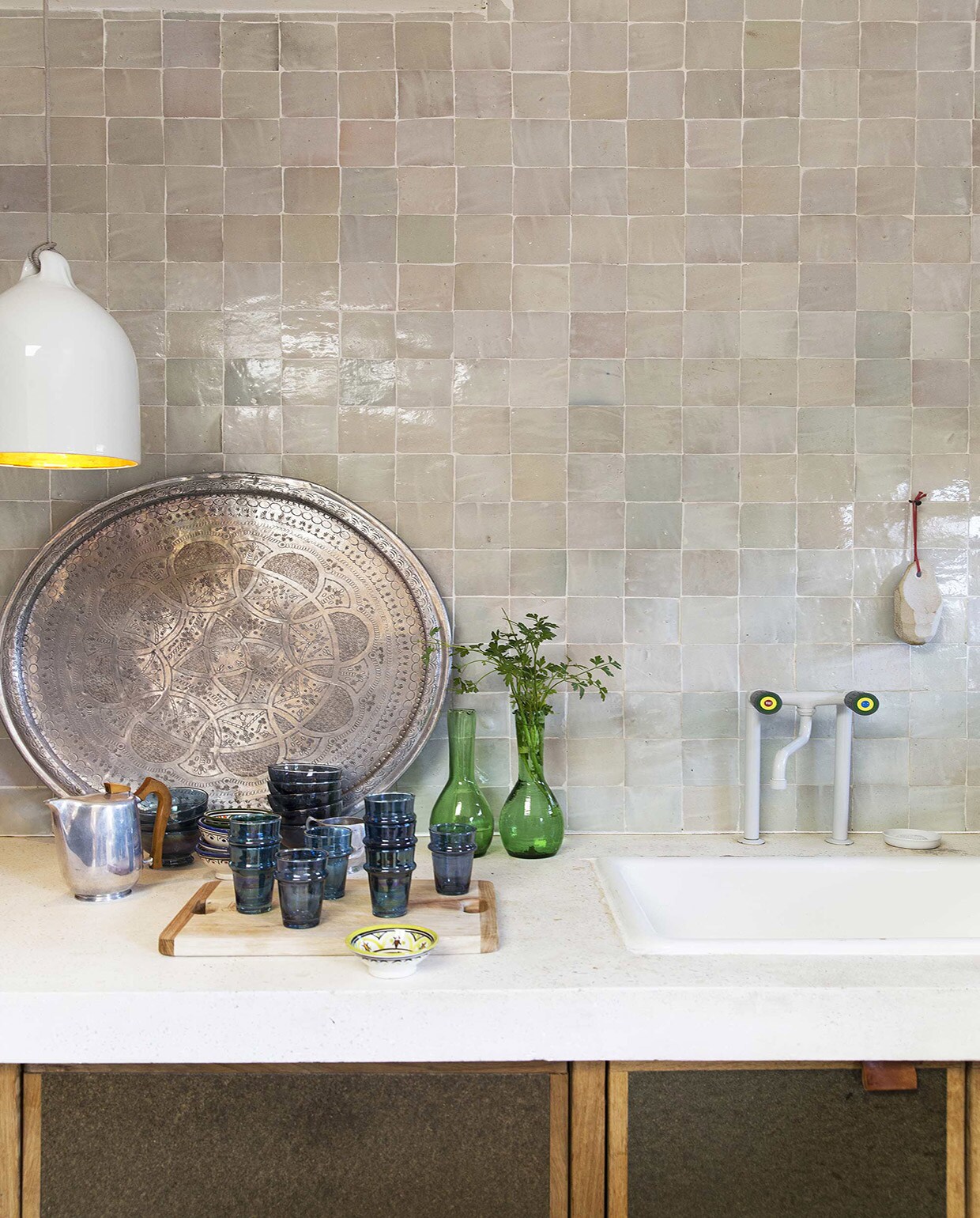 Handgebakken Marokkaanse tegels van Household Hardware per m² en wit marmeren terrazzo aanrecht (House of Bouw). Dienblad, blauwe bekers per stuk, groene karafjes per stuk (Household Hardware). Bufferlamp van Wieki Somers (Pols Potten). Keukenkraan(FAR). Theepot (Neef Louis). Overig privébezit.