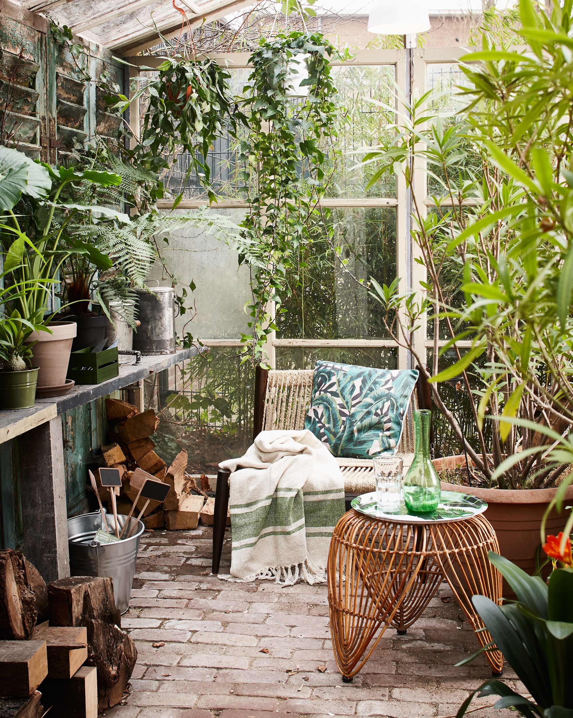 Stoel (Madam Stoltz). Kruk (l’Etoile Conceptstore). Kussen Tropical Banana Leaf green (Livv Lifestyle). Dienblad met bananenblad, groen kratje, plaid (H&amp;M Home). Groene glazen karaf (Household Hardware). Zinken emmer, plantenetiketten, groen metalen plantenpotje, oude metalen voorraadbussen (Combitex). Overig privébezit.