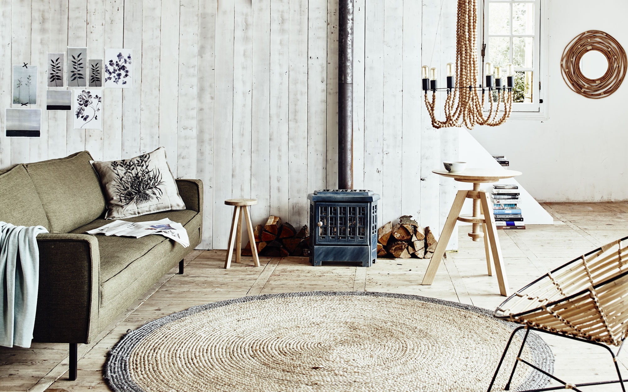 Bank Slimm, lichtblauw plaid, krukje, in hoogte verstelbare tafel (). Rieten vloerkleed van HK Living (vtwonen.nl). Spiegel Kubu met gevlochten bamboe lijst, ronde kuipstoel Kubu, hanglamp Beads (). Houtkachel privébezit.