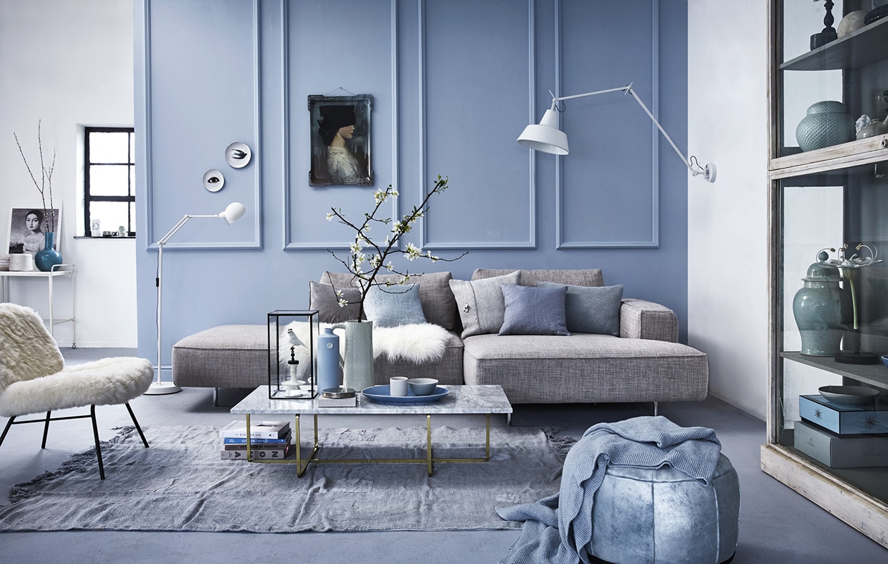 Muurverf Pale Wedgwood Absolute Matt Emulsion van Little Greene, klassieke wandprofielen P9040 op de muur van www.oracdecor.com ().  7780 van Gelderland (Dintra Design). Kussens v.l.n.r. fluwelen  (De Weldaad). Linnen kussenhoes (. Kussen (). Gebreid  (By Mölle). Stoel (). Wandlamp Chicago, vloerlamp Glasgow (). Salontafel (). Blauwe vaas van Elke van den Berg,  van J.C. Hermans (). Lichtgroene kan, vitrine (). Vogeltje (). Blauwe schaal, kom (). Kandelaar (). Poef ().  (Nordal). Vloerkleed (). Gebreid plaid ().  Ibn’de Ida, muurbordjes (). Vitrinekast (). Met daarin v.b.n.b.: lage Chinese pot met deksel, pot van keramiek (), mintgroene pot (). Blauwe doos (). Grijze doos privébezit.