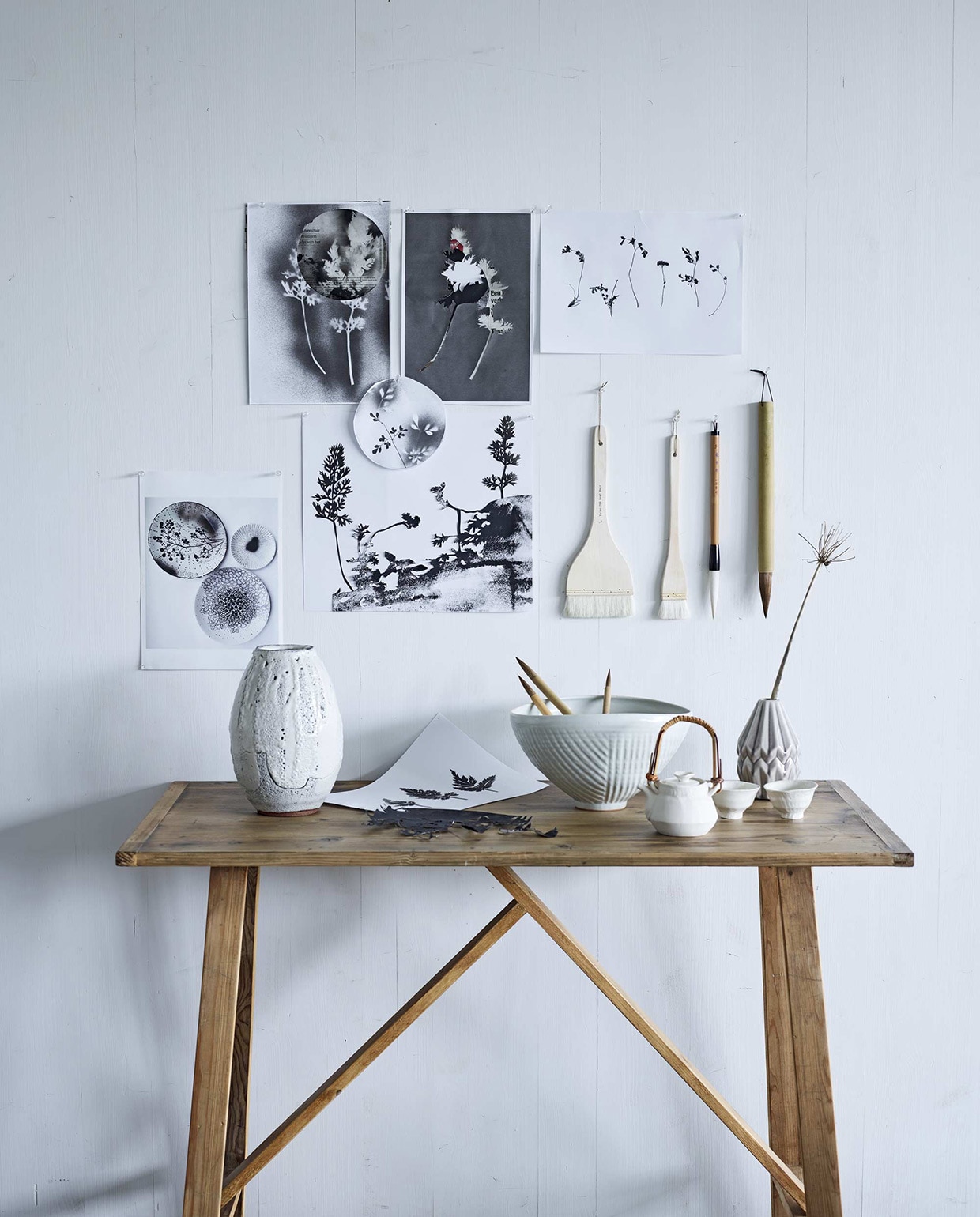 Aan de wand grafisch werk van Hedwig van Onna (). Sidetable (). Erop v.l.n.r. vaas Ogama, schaal, theeset bestaand uit een pot en twee bekertjes, penselen (). Kwasten (). Gevouwen vaasje ().,