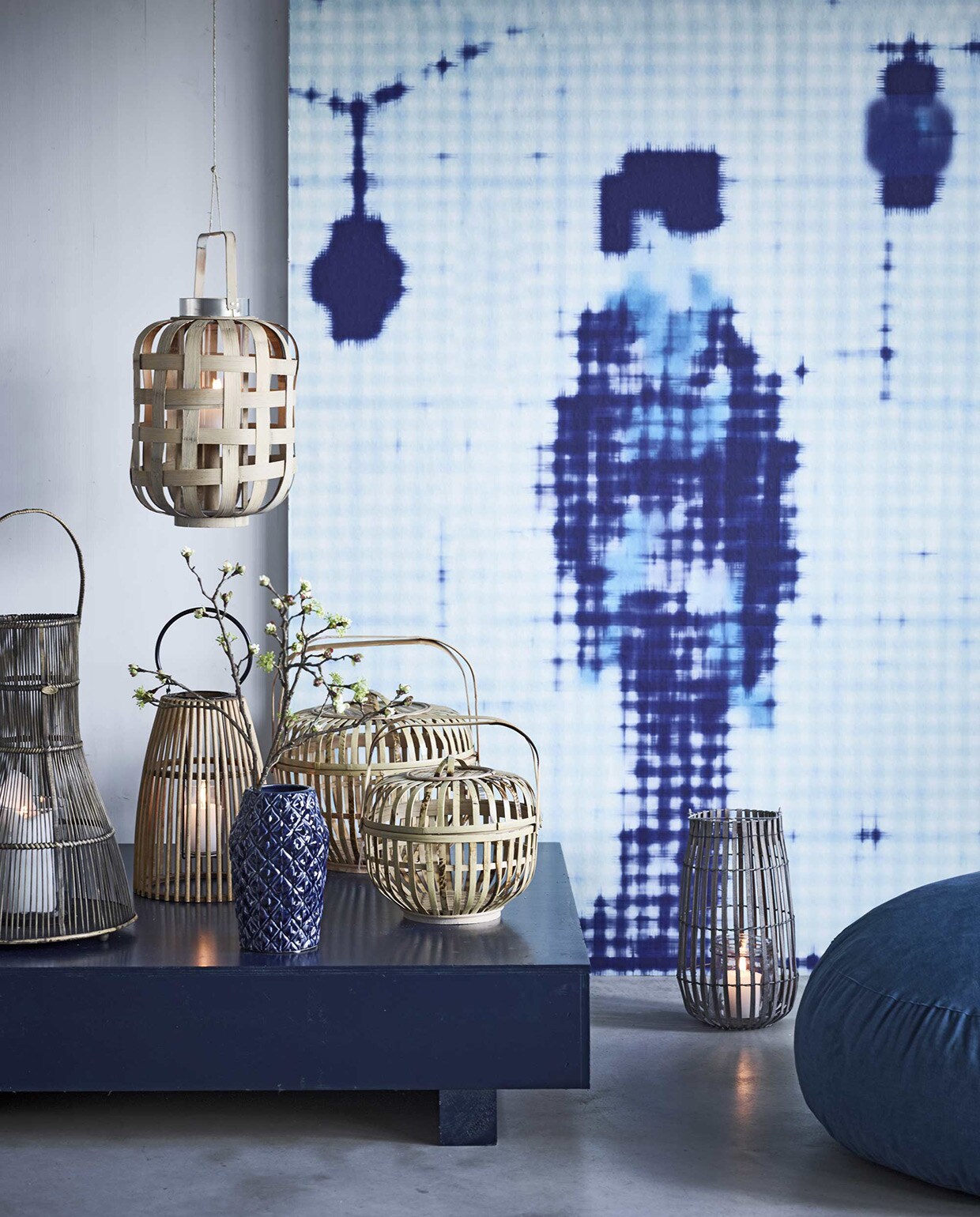 Behang uit de serie Addiction van NLXL, ontworpen door Paola Navone (). Lage kisttafel (). Poef Marrow (). Grote opbergmand van bamboe, medium mand ().  Braxton Hayley, , op de grond:  House Doctor Bars, hangend: lantaarn Strip van Pols Potten,  van Bloomingville (vtwonen.nl). Bloesemtak € 17,50 ().