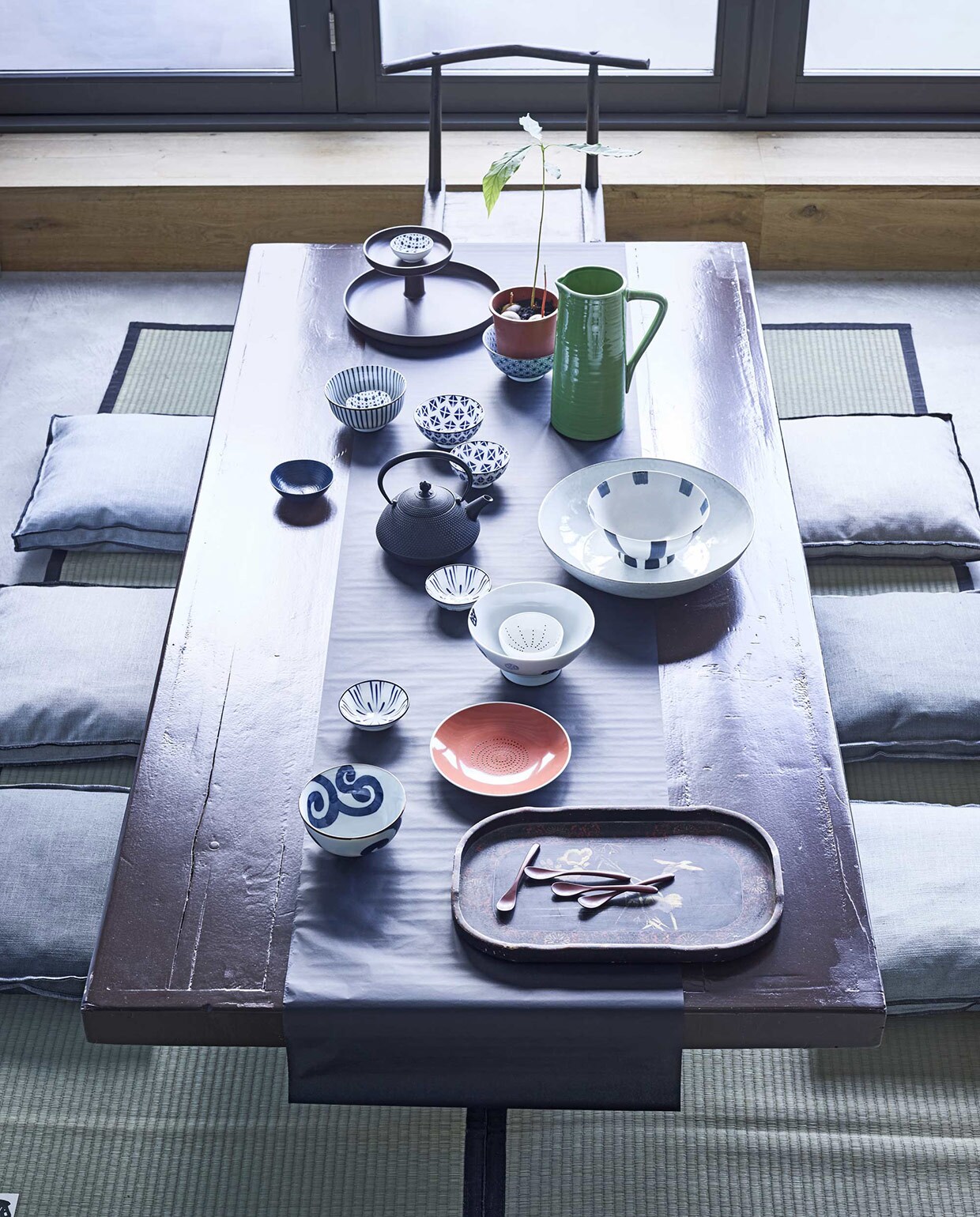 Tafel, geschilderd in kleur Chocolate van Little Greene (). Tafelloper gemaakt van zijdepapier (). Op de vloer tatamimatten (). Dienblad vooraan (). Etagère achteraan (). Groene kan (). Kom met streep, met bloem, met lijn en met krul, blauw, Japanse theepot van gietijzer (). Kommetjes Beijing Blue, klein schaaltje met stippen, rood bord (). Grotere schaal (). Kussens Lee ().