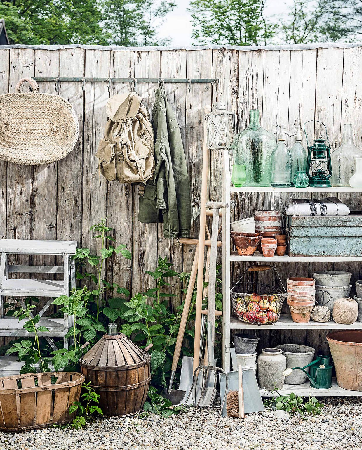 Trapje, stellingkast, fles in mand, rugzak, oude hark, groene vaas, glazen vaas, spuitflessen (Burbri Antiek). Kapstok, houten mand, oude lantaarn, kleine groene vaasjes, terracotta potten met bruin glazuur, witte bloempotten, grijze bloempot, grijze stenen vaas met ronde hals (De Weldaad). Rieten tas met leren details (Sukha Amsterdam). Jas, opgevouwen stof met blauwe streep (Six and Sons). Nieuw tuingereedschap, groene gieter (De Wiltfang). Handveger, veegblik (Loods 5). Groene lantaarn vanaf (Dille &amp; Kamille). Terracotta bloempotten, oogstmand (Fleurmonde). Gereedschapskist (Brût Amsterdam). vtwonen 07-2017 | Fotografie Sjoerd Eickmans | Styling Danielle Verheul