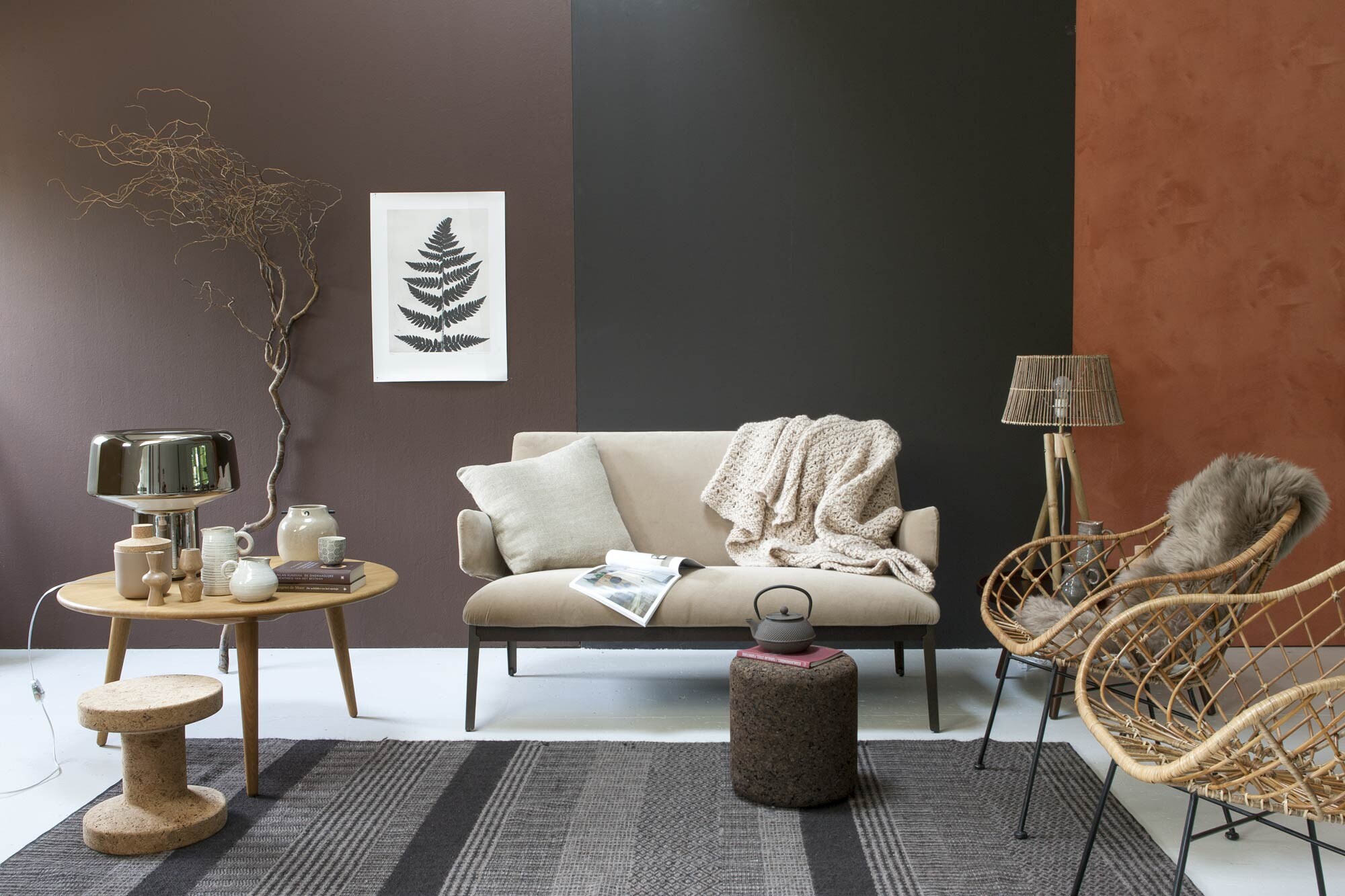 Muurverf van links naar rechts: Spanish Brown nr. 32, Chocolate Colour nr. 124 (Little Greene), kalkverf Marrakech (Carte Colouri). Bank Arflex hug sofa, vloerkleed Casalis (Friday Next). Salontafel van geolied eiken van Hans J. Wegner, tafellamp Drop van Diesel by Foscarini, naturel kurken bijzettafel Cork van Vitra, donkerbruine kurken bijzettafel (Mobilia Woonstudio). Rotan stoelen, bamboe lamp van Tine K Home, poster Fern (l’Etoile Conceptstore). Plaid Indie (Sukha Amsterdam). Linnen kussen van Aai, espressokopjes, theepot (Loods 5). Schapenvacht (Ikea). Grote houten kandelaars Sam van Casa Vivante achter de stoel, voorraadpot met deksel New Norm van Menu, kannen van Case Vivante, kleine houten kandelaars van Kikkerland op de tafel links, lichtbruine vaas op tafeltje links Woody van House Doctor (vtwonen.nl). Tak privébezit.
