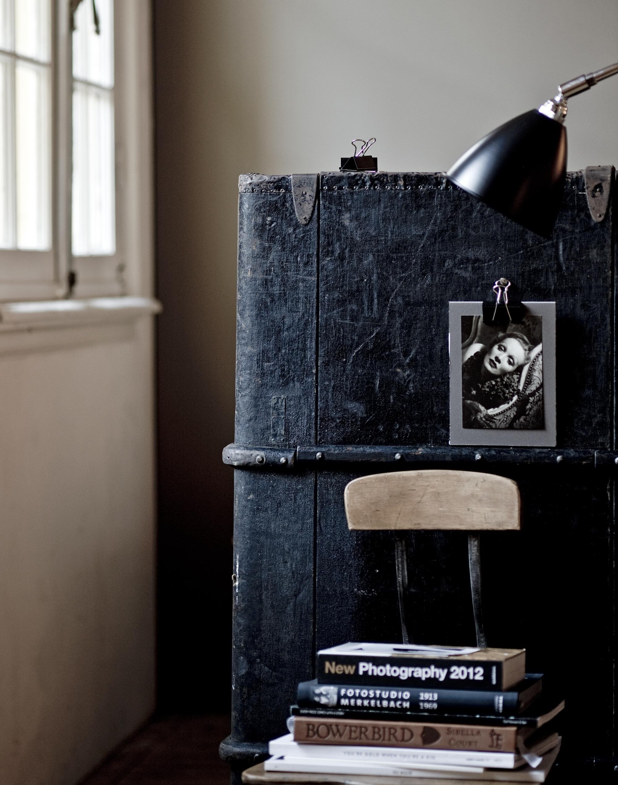Ansichtkaart (). Zwarte papierklemmen, grijs karton (). Oude hutkoffer (). Oude naaimachinestoel (). Staande lamp ().