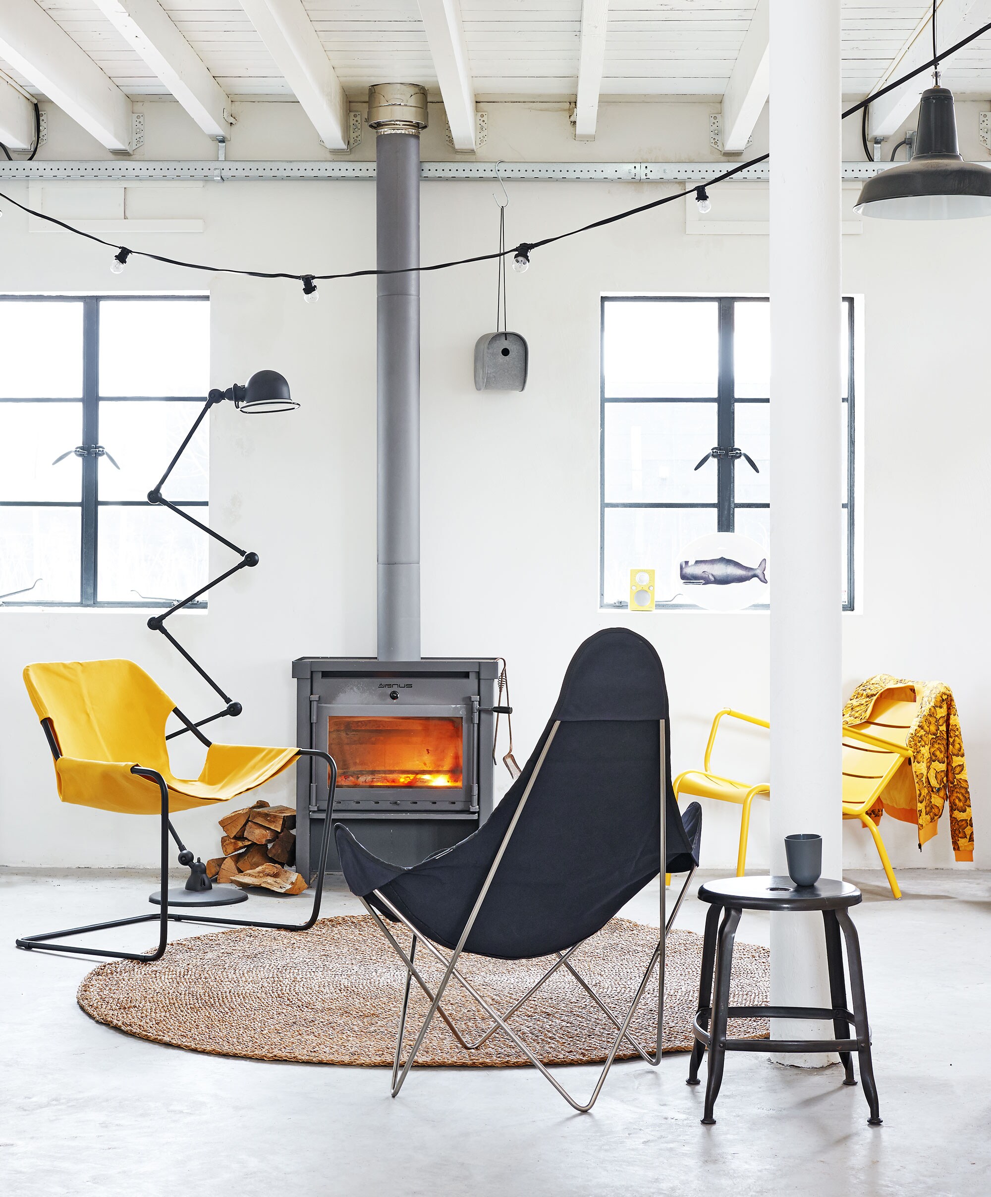 Paulistano Chair met katoenen hoes,  met katoenen hoes,  van Fermob,  van Chaises Nicolle,  van Eternit (Extra Vert). Vloerkleed van zeegras Ø 200 cm, Tivoli Audio radio Pal (niet meer leverbaar in geel) (). Jieldé vloerlamp ().  (Hema). Snoerlamp light chain van House Doctor (vtwonen.be).  (Urbans and Indians). Jasje ().