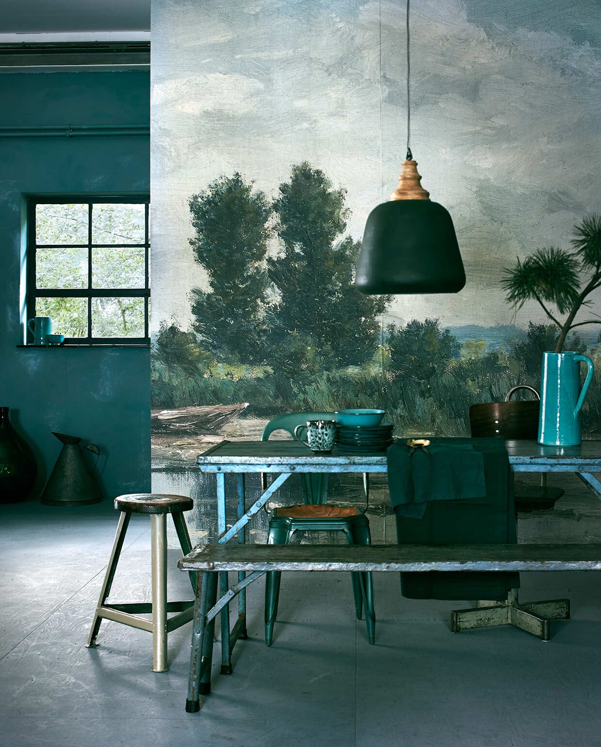Behang op basis van Plas bij Loosdrecht van Willem Roelofs, gedownload uit het archief van het Rijksmuseum. Het fotobehang werd op maat gemaakt, (www.bnwall-coverings.com). Muurverf rond het raam Pure &amp; Original Classico krijtverf, kleur Blue Reef (De Ru). Smalle tafel Market table, vouwbankje (Raw Materials). Turkooise stoel Forbach, stoel met kruisvoet (Brût Amsterdam). Kruk (Combitex). Ontbijtborden, kom (Serax). Tafellaken, servet (H&amp;M). Hoge geglazuurde kan, kan in raamkozijn; kom (In Petto). Op de grond: groene fles, oliekan (Raw Materials).