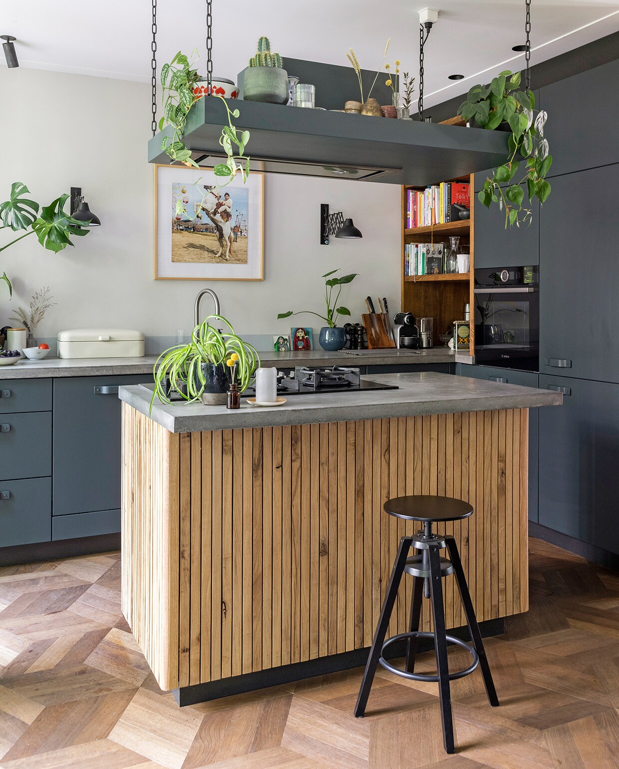 De keuken werd gebouwd door Van Venrooij Interieurbouw. De latjes rondom het kookeiland bevestigde Philip samen met zijn schoonvader. Betonnen aanrechtbladen Maarten Zwartjes. Kruk Ikea. Vloer Soares Parket. Spotjes Brink Licht. Wandlamp Made. Foto aan muur van Marieke, lijst Jollijst. Broodtrommel rommelmarkt IJ-Hallen. Bakjes e.d. op werkblad IJ-Hallen en Hema. Bakjes e.d. op schouw rommelmarkten, Mica en Loods 5. vtwonen 04-2020 | fotografie Margriet Hoekstra