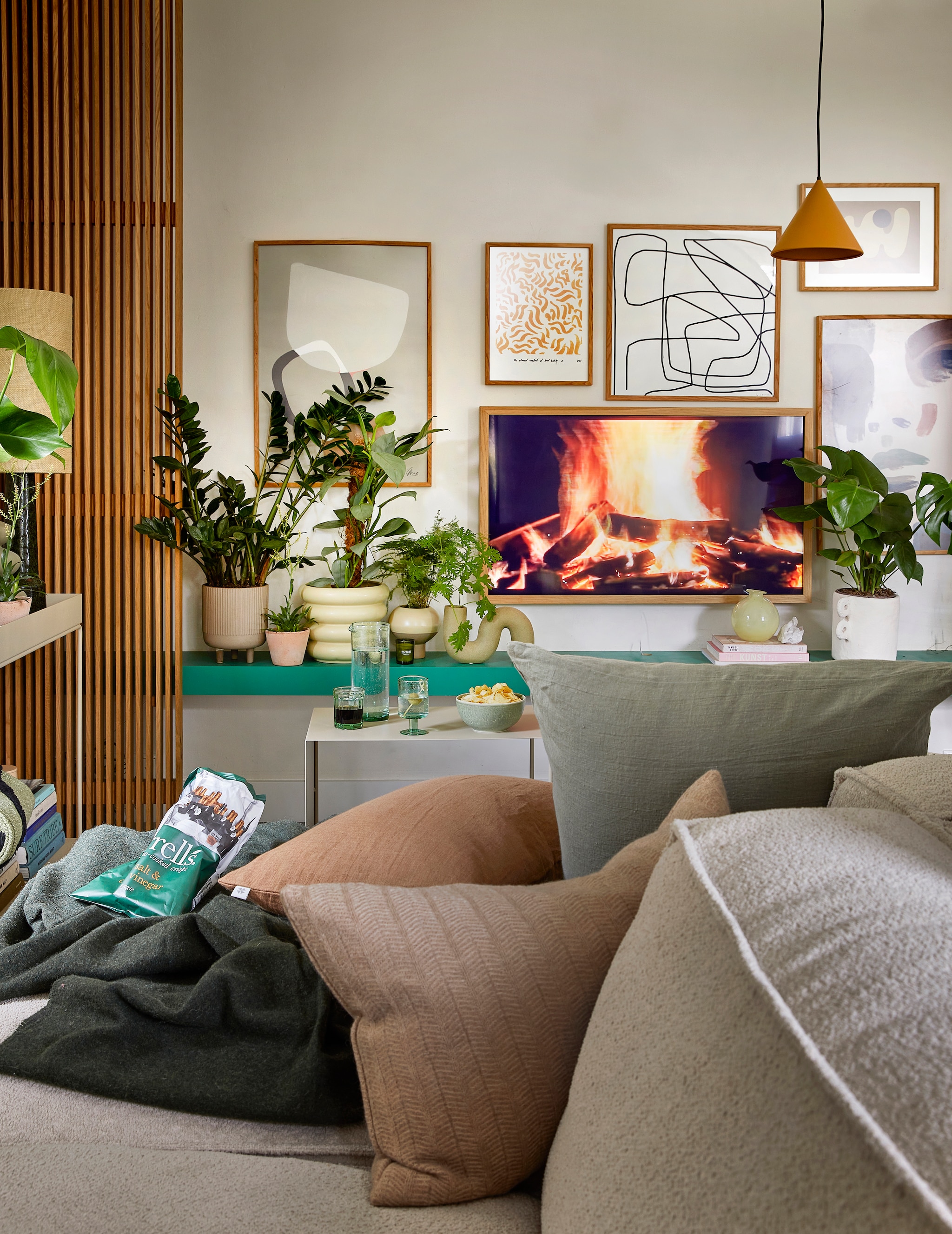 Linnen kussen Olive, 60×60 cm € 69,-, linnen kussen Cinnamon, 40×60 cm € 59,- (bymolle.com). Lichtbruin kussen met visgraatmotief Kata van Oyoy, 40×60 cm € 57,80 (wonenmetlef.nl). Donkergroene merinowollen deken van McNutt, 200×145 cm € 100,-, groen glas van Serax, medium € 9,50, groen aardewerken schaaltje Miscellaneous € 7,- (vanmanenaantafel.nl). Grijze terracotta plantenpot op poten van Kristina Dam, 18x18x22 cm € 89,-, op de muur v.l.n.r.: poster 03 van Studio Mae van Paper Collective, 50×70 cm € 55,-, poster Comfort Yellow, 30×40 cm € 35,-, poster Her van Paper Collective, 50×70 cm € 55,-, eikenhouten lijst van Paper Collective, 30×40 cm € 35,-, eikenhouten lijst van Paper Collective, 50×70 cm € 55,-, gerecycled wijnglas Oli van Ferm Living € 25,-, gerecyclede glazen karaf Oli Jug van Ferm Living € 39,-(byjensen.nl). Terracotta bloempot Rosa, 12 cm (Ø) € 9,50 (bymolle.com). Beige geribbelde pot Awa Large in Butter van Oyoy, 25,7×22 cm (Øxh) € 70,55, gele vaas Hagi van Oyoy, 15×15 cm € 34,- (wonenmetlef.nl). Vaas Object in Matt Olive van HKliving € 34,99, witte papier-maché pot met oren van Serax € 55,-, oranje ijzeren hanglamp Triangle van HKliving, 25×22 cm € 95,- (vtwonen.nl). Ecru glazen vaas € 24,95, planten vanaf € 4,95 (stadstuindebloemenpoort.nl). Bergkristal € 75,- (eduard-leiden.nl). Televisie The Frame met eikenhouten lijst, vanaf € 1099,- (samsung.com). Ecru elementenbank Square van Easy Sofa, per module vanaf € 605,- (hoekbankxxl.nl). Lijntekening en boeken privébezit. vtwonen 02-2023 | Styling: Femke Pastijn | Fotografie: Peggy Janssen