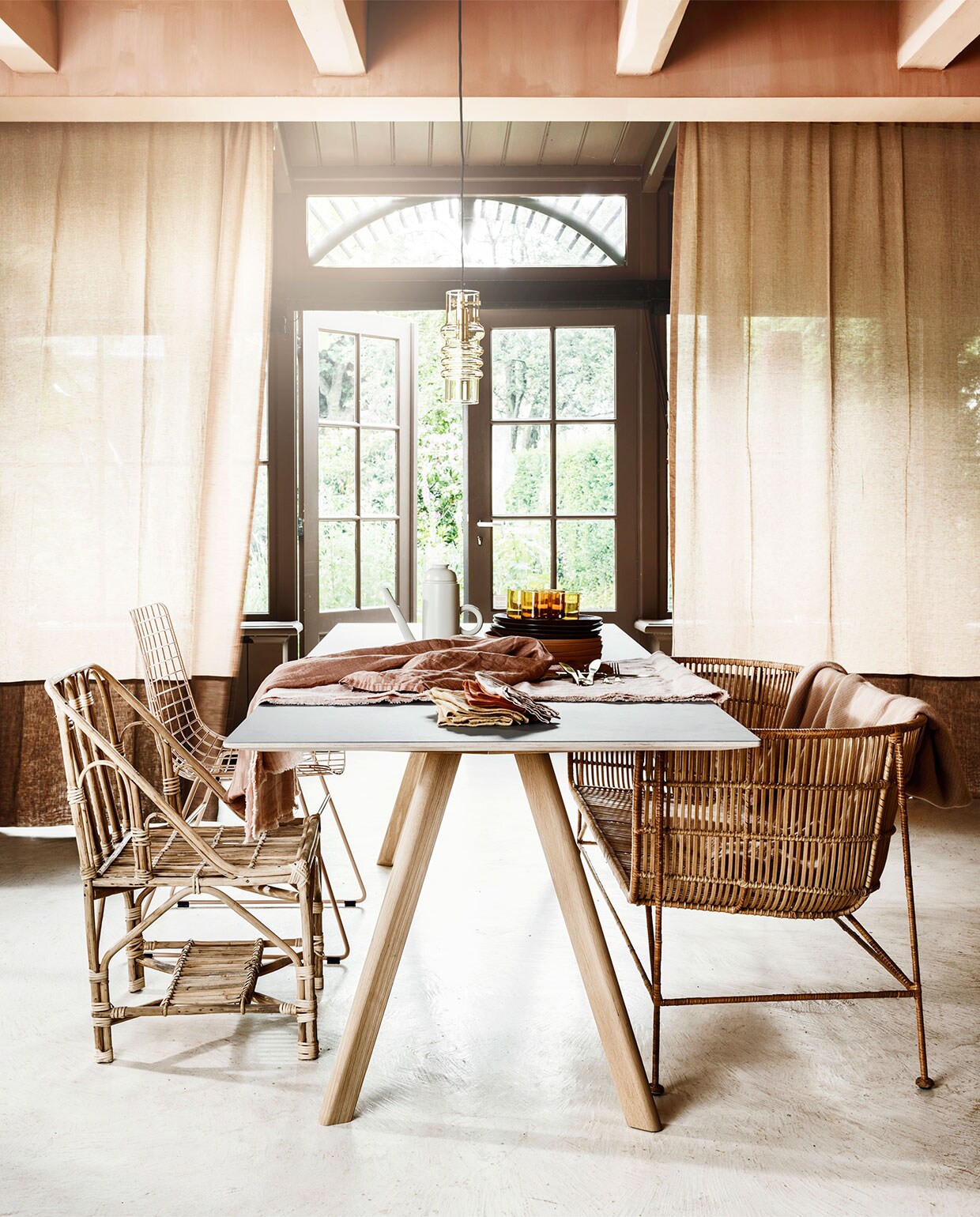 Gordijnen van linnen Sutton House van Chivasso per meter € 144,50 (jab.de). Tafel van Hay, 250×90 cm € 1389,-, rotan bank, 140 cm breed € 726,-, stoel Wire in roze € 169,-, stoel van bamboe van Madam Stoltz, € 230,95, amberkleurige lamp van Normann Copenhagen € 200,- (vtwonen.be). Op tafel: koffiepot van Normann Copenhagen € 80,50, roze bord vanaf € 9,95, donkerrood bord € 16,50 (vtwonen.be). Onderste tafelkleed van zachtroze linnen € 95,-, gele servetten per twee € 14,95 (hkliving.nl). Overige servetten € 10,- (gabrielle-paris). Tafelkleed van terrakleurig linnen € 150,- (weldaad.com). Messingkleurig bestek € 21,99 per driedelig couvert (nordal.dk). Plaid van Hay € 75,- (eijerkamp.nl). vtwonen 08-2019 | styling Marianne Luning | fotografie Stan Koolen