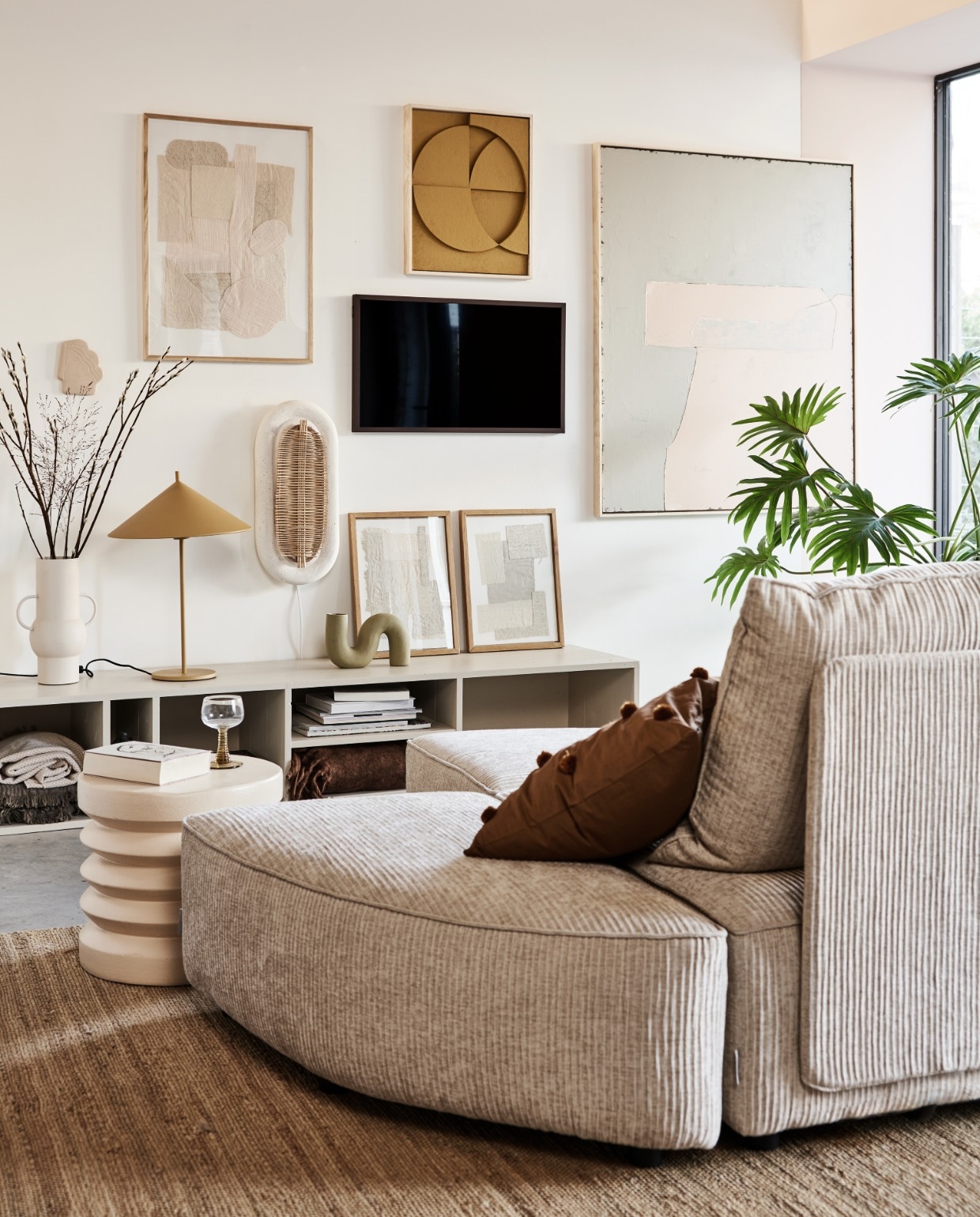 Televisie The Frame 32 inch € 429,-, verwisselbare walnoothouten lijst The Frame € 129,- (samsung.nl). Kast in kleur Skimming Stone 241 van Farrow & Ball AFMETING (combitex.nl). Handgemaakte ovalen wandlamp NAAM € 299,- (lanena-home.com). Sofa Hunter bestaat uit diverse losse onderdelen: poef € 419,-, element met rug € 1009,-, element zonder rug € 419,- (zuiver.nl). Bruin sierkussen met pompons van MERK € 29,95, roze bijzettafel van MERK € 159,-, vaas van MERK AFMETING € 47,95 (vtwonen.nl). Hennep vloerkleed 180×280 (bxl) € 395,-, olijf/nude-kleurig abstract kunstwerk (rechts) 100×120 cm (bxh) € 549,-, okergeel kunstwerk boven tv van 43x4x53cm (bxdxh) € 329,-, taupekleurig wandornament Face € 37,95, crèmekleurige bijzettafel 38×36 cm (Øxh), wijnglazen met groene voet € 9,95, okergele lamp Triangel € 149,- (hkliving.nl). Stoffen kunstwerk in eikenhouten lijst € 89,-, kunstwerken in lijst op kast, per stuk € 69,- (sur-atelier.nl). Bruine en beige katoenen plaids in dressoir 130×170 cm per stuk € 45,99 (zarahome.com). Donkerbruin plaid rechts in dressoir 130×170 cm (bxl) € 65,- (maisonnl.com). Overig privébezit. vtwonen 02-2022 | styling Esther Jostmeijer | fotografie Bart Brussee