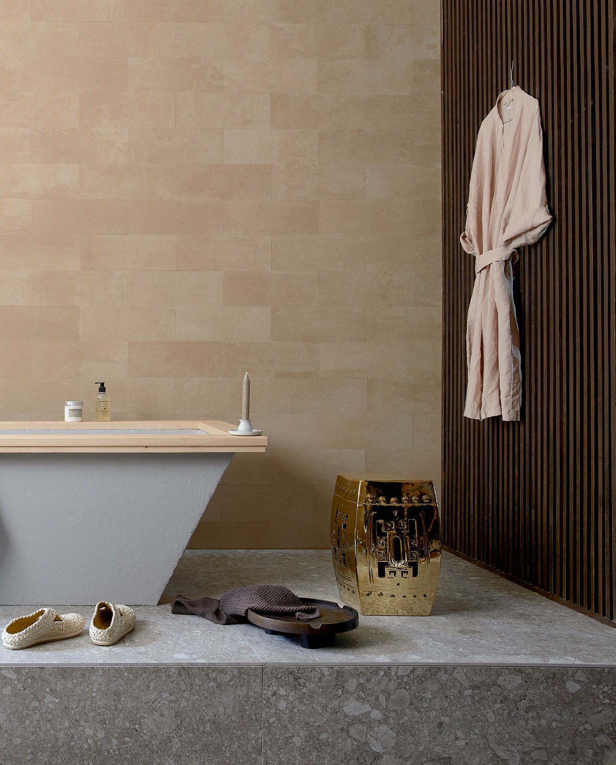 Leren wandtegels uit de Colorado collectie, kleur 3901 desert, als afgebeeld € 4500,- (ohmannleather.com). Podiumvloer met vloer-en wandtegel Composite Light Grey van vtwonen, 120×120 cm per m² € 79,95 (vtwonentegels.nl). Bad betonlook met houten rand, op maat gemaakt, prijs op aanvraag, lattenwand, prijs op aanvraag (com-anders.nl). Kraan Grip van vtwonen € 596,- (vtwonen.nl). Ecru handdoek € 14,99, schaal € 24,99, bruine handdoek € 5,99, linnen ochtendjas € 39,99 (hm.com). Schoenen € 105,-, (sukha.nl). Kruk Temple € 386,50 (polspotten.nl). Rieten mand € 22,50 (loods5.nl). Overig privébezit.