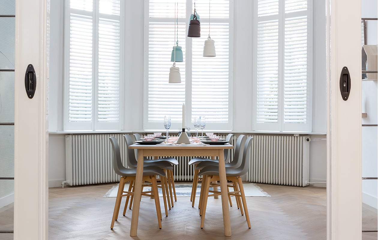 Shutters prijs op aanvraag (jasno). Eetkamertafel Pause, 200x85x72 cm (bxdxh) € 640,- (eijerkamp). Eettafelstoelen Langue Avant Garde Dining Chair, 50x51x78 cm (bxdxh) per stuk € 229,- (www.norr11.com). Hanglampjes Cable Light van porselein, per stuk € 179,- (patrickhartog). Diverse wandplankjes prijs op aanvraag (www.fijnhout). Groene vaas € 24,95 (www.vtwonen.nl). Op tafel: champagneglazen Figures € 11,25 (www.estherx). Blauwe kom van vtwonen, Ø 14 cm € 6,95, grijze kom van vtwonen, Ø 14 cm € 6,95, grijs bord van vtwonen, Ø 16 cm € 6,95, blauw bord van vtwonen, Ø 26,5 cm € 16,95, blauwe serveerschaal van vtwonen, Ø 30 cm € 34,95 (www.vtwonen.be). Betonnen kandelaars Conic, per stuk € 29,95 (www.puik-art). Vilten loper € 65,- (Vilta Amsterdam). Roze schaaltjes, glaasjes, Mariabeelden privébezit.
