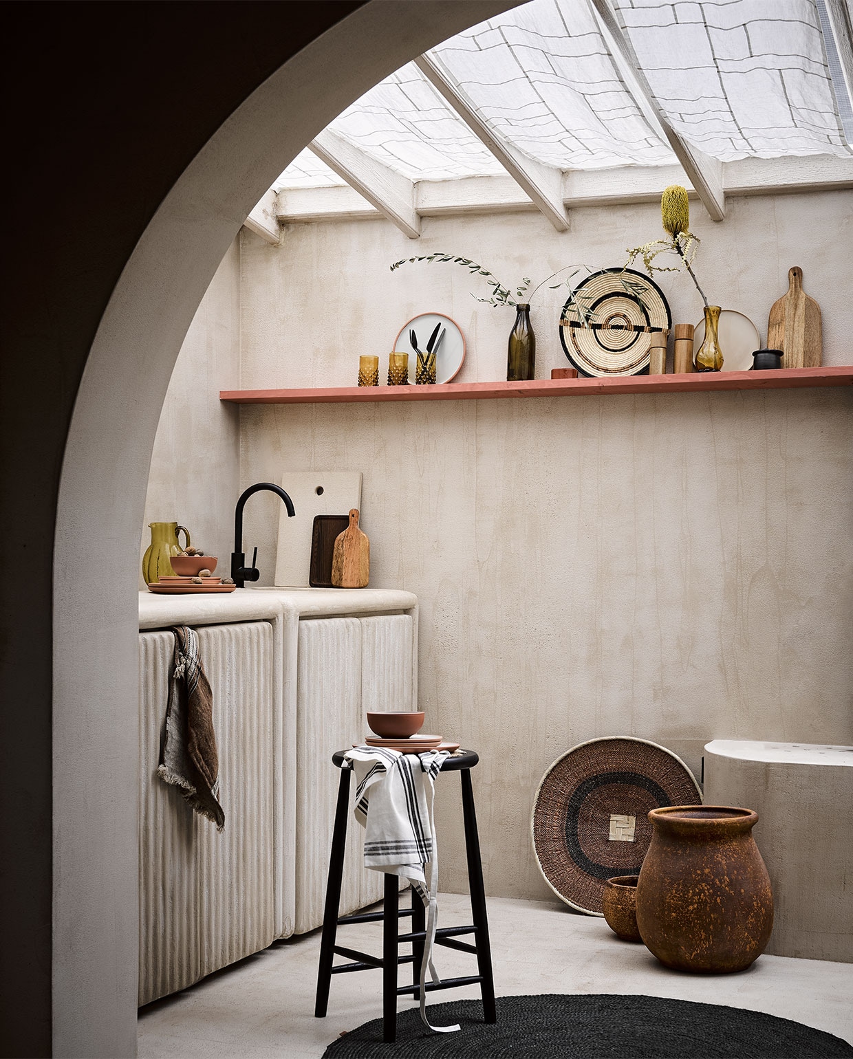 &lt; Linnen gordijnsheets gemaakt met pojagi techniek, prijs op aanvraag (bymolle.com). Plank geverfd in lakverf kleur Book Room Red No. 50 van Farrow &amp; Ball, per 2,5 liter € 97,- (deruamsterdam). Zwart bestek Stella van Blomus op plank, 16-delige set € 129,99, acaciahouten peper- of zoutmolen van AdHoc, 17 cm (h) € 29,99, 14 cm (h) € 24,95, beige bord Terres de Reves in Misty Grey van Serax, 22 cm (Ø) € 18,40, dienblad Heii van Serax, 25×16 cm € 26,95, zwart rond vloerkleed Eternal van Ferm Living, 120×120 cm € 94,50 (vtwonen.be). Microcement stuc op wand en vloer, prijs op aanvraag, inbouwkeuken met kraan per unit, vanaf € 2000,-, gestuukt dienblad tegen achterwand € 75,-, grote bruine vaas op de grond € 149,95, kleine bruine pot € 62,50, terra servies met groene binnenkant, schaaltje € 11,95, ontbijtbord € 14,95, groot bord € 16,95, klein terra schaaltje op plank € 14,95 (lanena-home.com). Houten snijplank groot € 12,99, klein € 9,99, wit schort met zwarte streep € 7,99 (hm.com). Droogbloemen (plantje.nl). Amberkleurig glas op plank met tak, per stuk € 13,-, mosterdkleurige fles met olijftak € 39,-, mosterd-kleurige glazen vaas met sierlijke vorm € 99,-, zwarte suikerpot € 47,-, mand met witte rand op grond, 58 cm (Ø) € 59,-, geweven mandschaal small op plank € 73,-, groene karaf op keukenblok art deco € 63,-, donkerbruine theedoek met streep van Libeco € 27,- (couleurlocale.eu). Zwarte kruk met rotan bovenkant J165B van Møblér € 689,- (homestede).