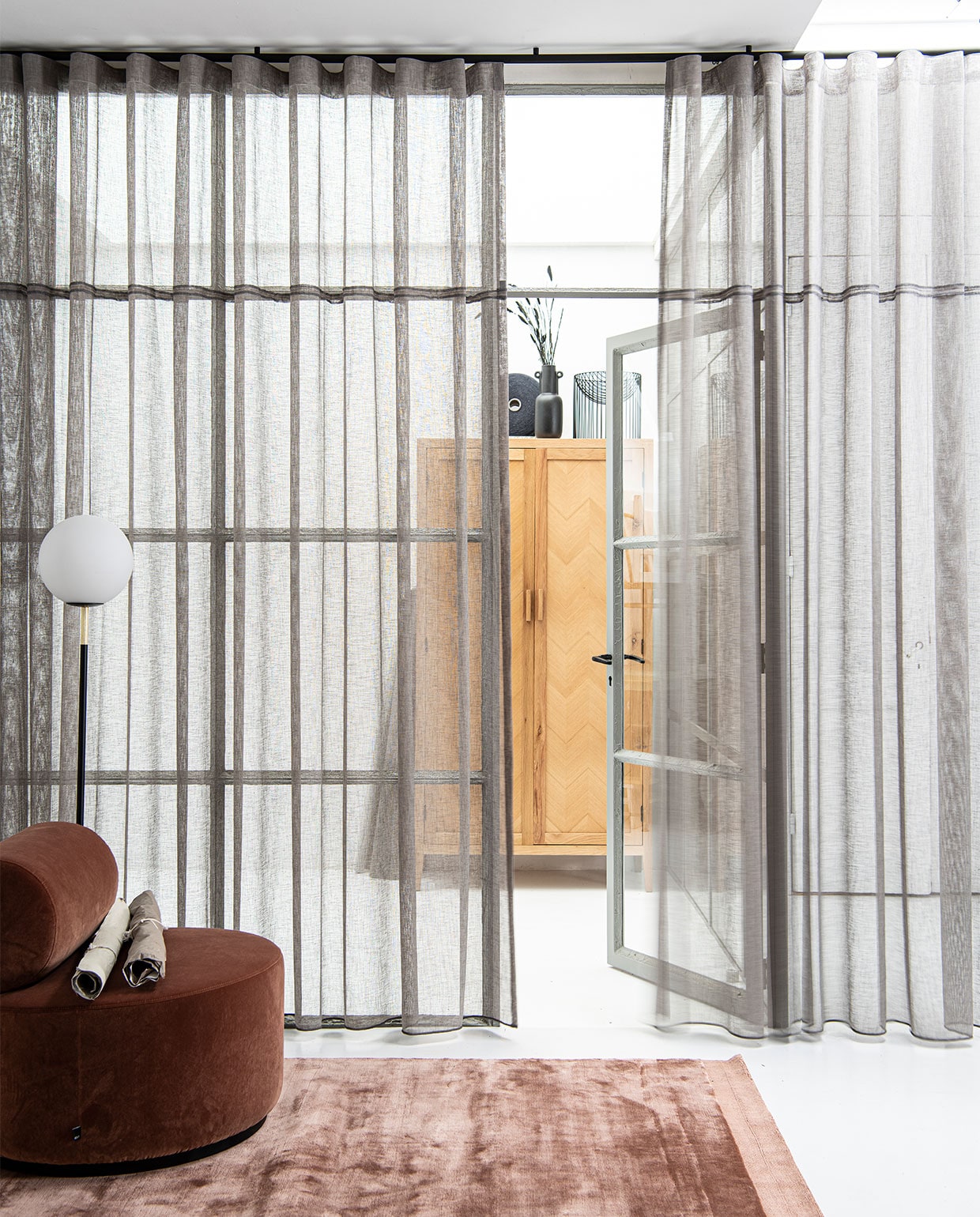 Gerecyclede gordijnstof uit pet-afval in kleur Stro (21), stoflengte 320 cm, per meter € 39,99 (ahouseof­happiness.com). Matzwarte, aluminium roederail 25 mm (Ø) met eindkap Sinus en zwarte plafond­afstandsteun 20 mm, compleet geassembleerd, per meter € 90,- (interstil). Fauteuil Sinclair in Magnolia € 839,- (festamsterdam.com). Vloerkleed Terry in Magnolia, 160×230 cm € 699,- (festamsterdam.com). Vloerlamp Orion met opaal glazen bol € 195,- (zuiver.com). Eiken naturel garderobekast Tulang met visgraateffect, 190x100x50 cm (hxbxd) € 1095,- (loods5.nl). Klos van gerecyclede garens (ahouseofhappiness.com). Zwarte vaas met oren € 30,- (thingsilikethingsilove.com). Metalen schaal van Serax, prijs op aanvraag (dotshop).