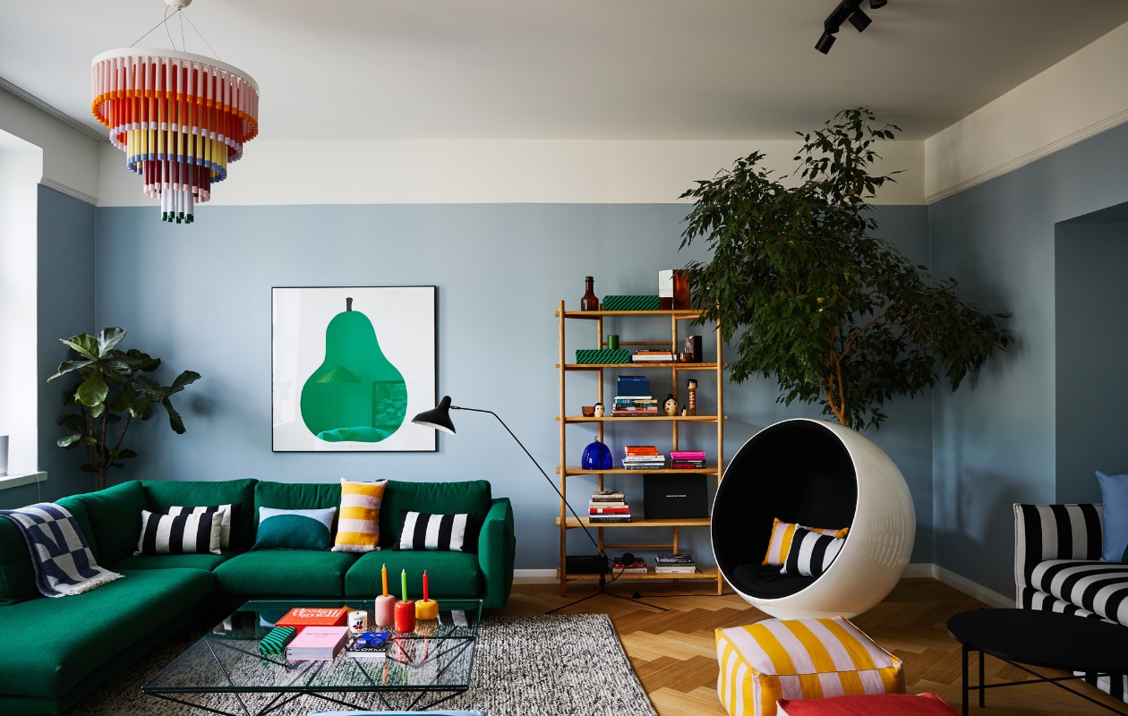 Bank Cosy Pocket, kroonluchter Cocktail, houten kast, kussens en poefen Hakola x Vuokko. Vloerkleed Marble Brink &amp; Campman. Vintage koffietafel Alanda Paolo Piva voor B&amp;B Italia. Bolstoel Ball Chair Eero Aarnio. Vloerlamp Mantis DCW Éditions. Poster Due, la pera van Enzo Mari voor Danese Milano.