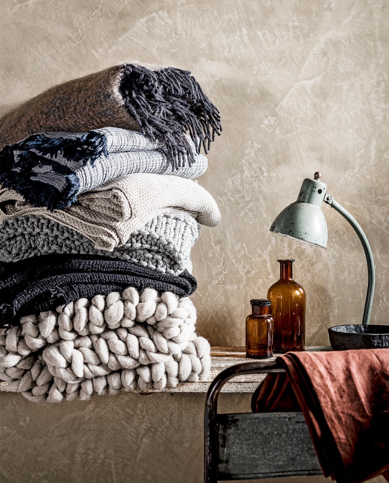 Van boven naar onder: mohair plaid van de Wolwaeren Shore Line collection in kleur Seaweed € 229,- (Studio Ro Smit). Vergrijsd blauwe gekreukte deken met franje, 150×210 € 99,- (Hay Amsterdam). Ecrukleurige gehaakte plaid € 69,95 (Dille &amp; Kamille). Grijze gehaakte plaid € 59,99 (H&amp;M Home). Zwarte wafeldeken Svärtan € 34,95 (Ikea). Grof gehaakte wollen deken,100×150 cm € 220,- (Vacht van Vilt). Metalen stoel € 59,-, sidetable € 229,95 (Raw Materials). Apothekerspotten vanaf € 9,95 (De Weldaad). Bureaulamp € 325,- (Neef Louis). Zwarte kom Svärtan € 5,99 (Ikea). vtwonen 02-2017 | styling Danielle Verheul | fotografie Sjoerd Eickmans