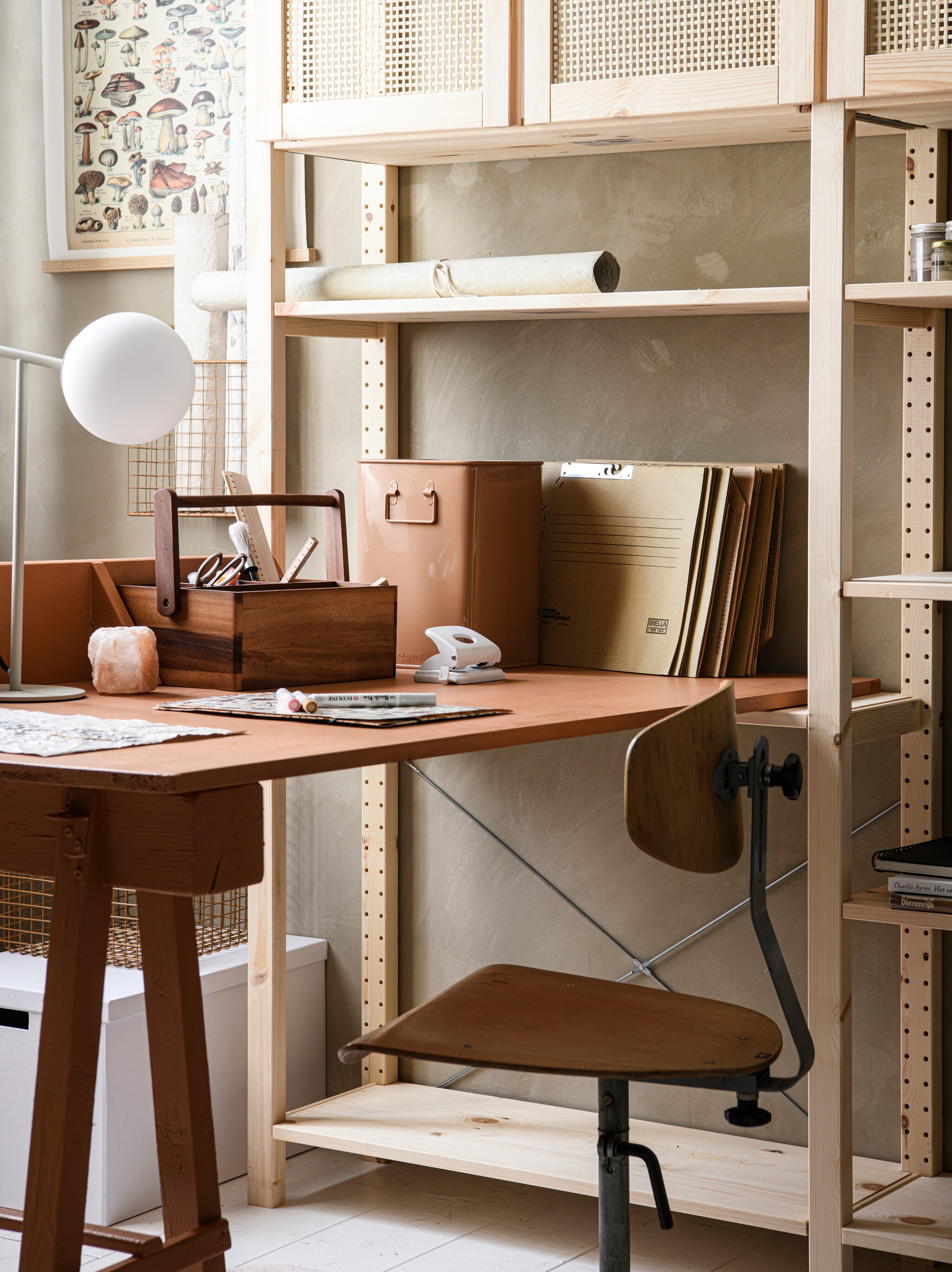 Grenenhouten stellingkast Ivar met 3 elementen/planken, 259x30x179 cm (bxdxh) € 378,-, kastdeuren, 42×83 cm, per 2 € 40,-, totaalopstelling zoals op foto € 459,-, witte gerecyclede kartonnen opbergdoos Tjena, 32x35x32 cm € 4,99 (ikea.com). Limewash muurverf in Caramel, per liter € 30,- (bauwerk.com.au). Wandkleed aan stok Vintage Paddenstoel, 35×47 cm (bxh) € 56,99 (home24.nl). Metalen manden, 24x8x36 cm € 19,99, 32x29x29 cm € 25,95 (zarahome.com). Rollen Old-Dutch canvas Create your Own Canvas, A3-formaat € 17,95 (shop.mo-ca.nl). Vintage bureaustoel, vanaf € 45,-, op maat gemaakt bureaublad met vakken, vanaf € 75,-, box op bureau, vanaf € 35,-, (com-anders.nl). Bureau en box geschilderd met krijtverf Classico in Kenyan Copper van Pure &amp; Original, per liter € 49,45 (pure-original.com). Tafellamp Nox van Loods 5 Goods, metaal en glas € 79,95 (loods5.nl). Acaciahouten opbergbak met 4 vakken en handvat € 24,95, houten meetlat, 20 cm € 2,50 (dille-kamille.nl). Overig privébezit. vtwonen 02-2023 | Styling Marit Saladini, fotografie Louis Lemaire