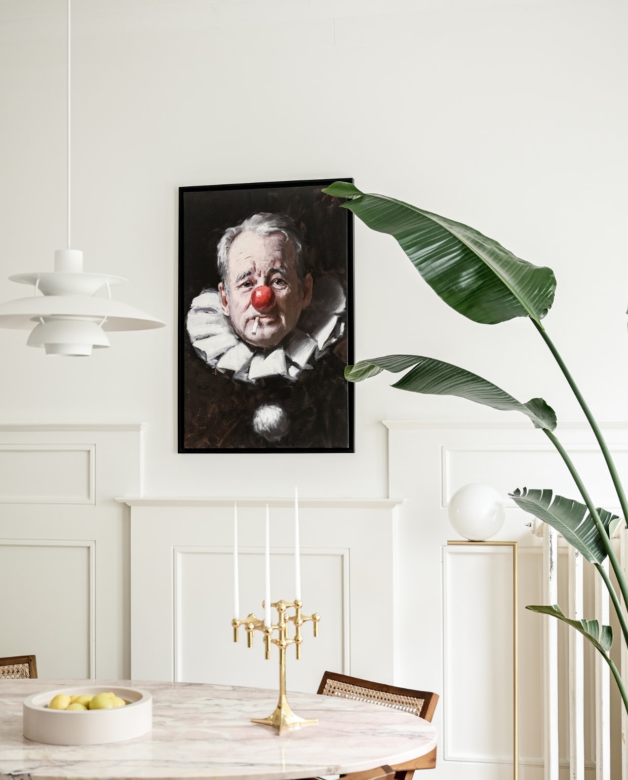 Eettafel en travertin fruitschaal Amphi van Stoned. Stoelen Detjer. Hanglamp PH5 van Louis Poulsen. Vloerlamp Flos. Olieverfschilderij Bill Murray van Tony Pro. Kandelaar Stoff.