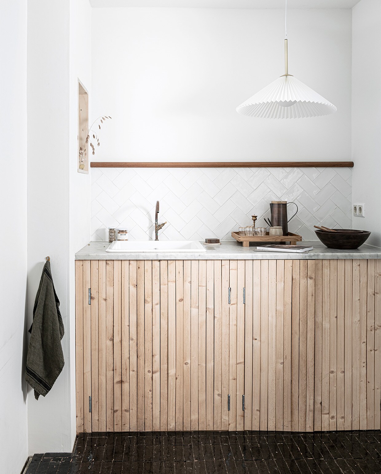 Latten keukenkast komt uit vtwonen special DIY 1. Grote vaas € 35,99, pan € 99,99, kom € 35,99, geruite shopper € 29,99 (zarahome.com). Marmeren dienblad € 24,99, marmeren snijplank € 24,99, marmeren taartplateau € 29,99, linnen schort € 19,99 (hm.com). Bruine glazen karaf met bol-dop € 32,95 (loods5.nl). Kleihanger € 44,50 (ohmyhome.nl). Keuken op maat gemaakt, prijs op aanvraag (fredconstant.nl). Overig privébezit. JA | vtwonen special DIY  1 09-2020 | productie &amp; styling Kim van Rossenberg | uitvoering Richard van Meerveld | fotografie Sjoerd Eickmans