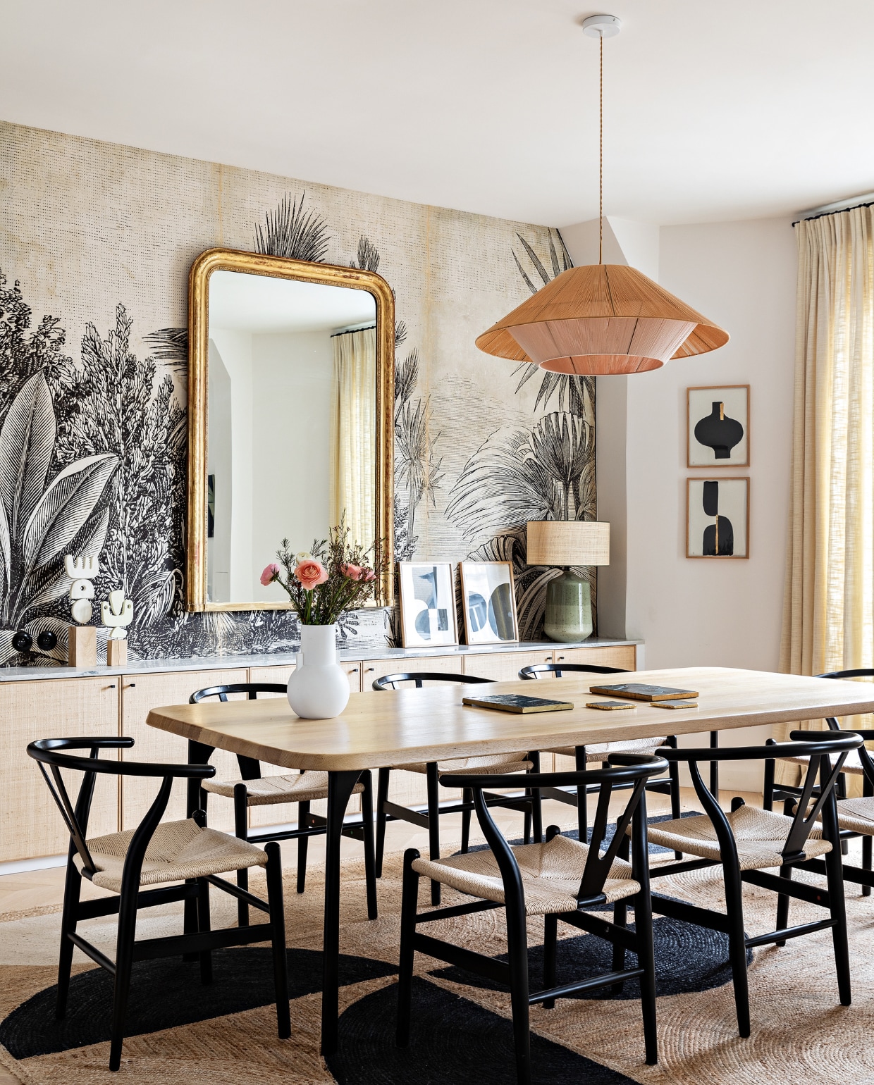 Eiken tafel Oasis van Maison Sarah Lavoine. Stoelen Carl Hansen &amp; Søn. Hanglamp Maison Paloma. Spiegel vintage. Behang Le Monde Sauvage. Witte vaas HKliving. Lamp met groene voet Zara Home. Schilderijen Floating House Collection. Vloerkleed Elitis. Overig onbekend. vtwonen 12-2022 | styling Marie-Maud Levron | fotografie Yann Deret | tekst Anne-Catherine Scoffoni | tekstbewerking Christine van der Hoff