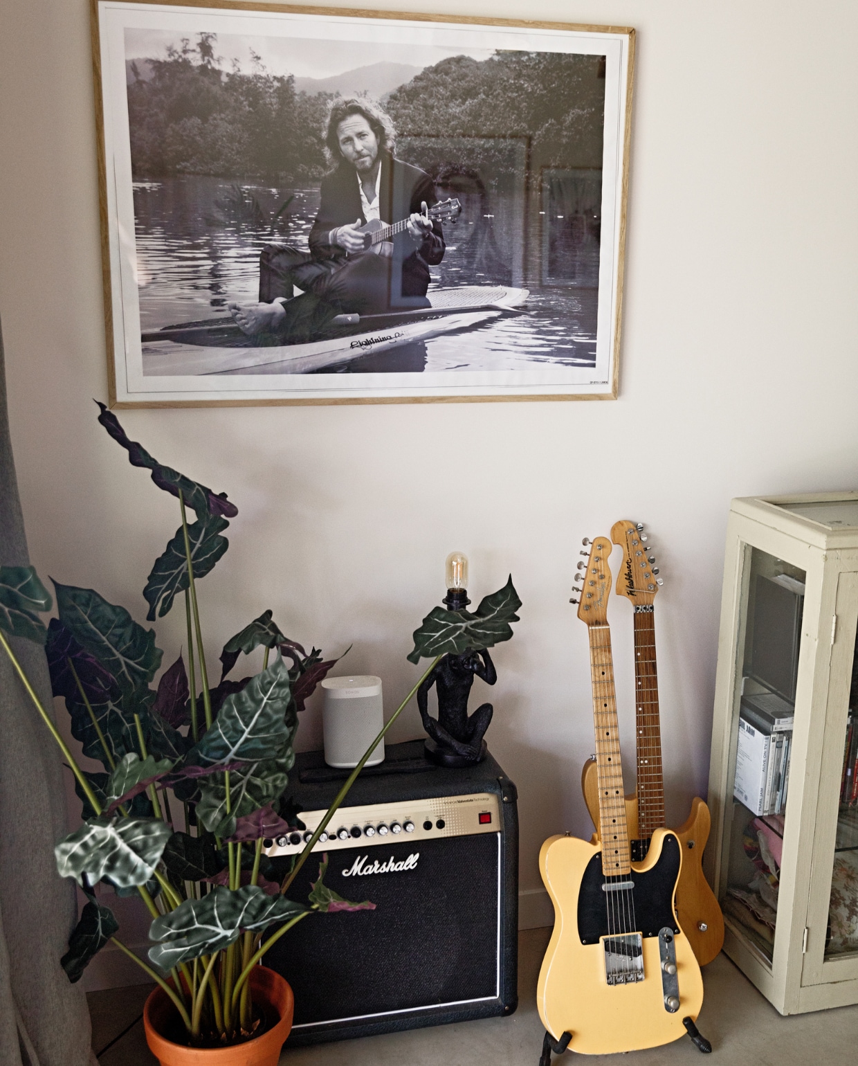 Muurkleur Luxurious Silk van Flexa Creations, vloer gevlinderd beton van Bull beton, gordijnen Kwantum, lijst Desenio, poster Eddie Vedder Amazon, nepplant The Goodstore, pot Intratuin, versterker Marshall van Kees Dee, speaker Sonos, zwarte kandelaar Xenos, kaars Sissy-Boy, gele gitaar Fender telecaster, bruine gitaar Washburn N2 Gooise Gitaren, kast Burbri Antiek.