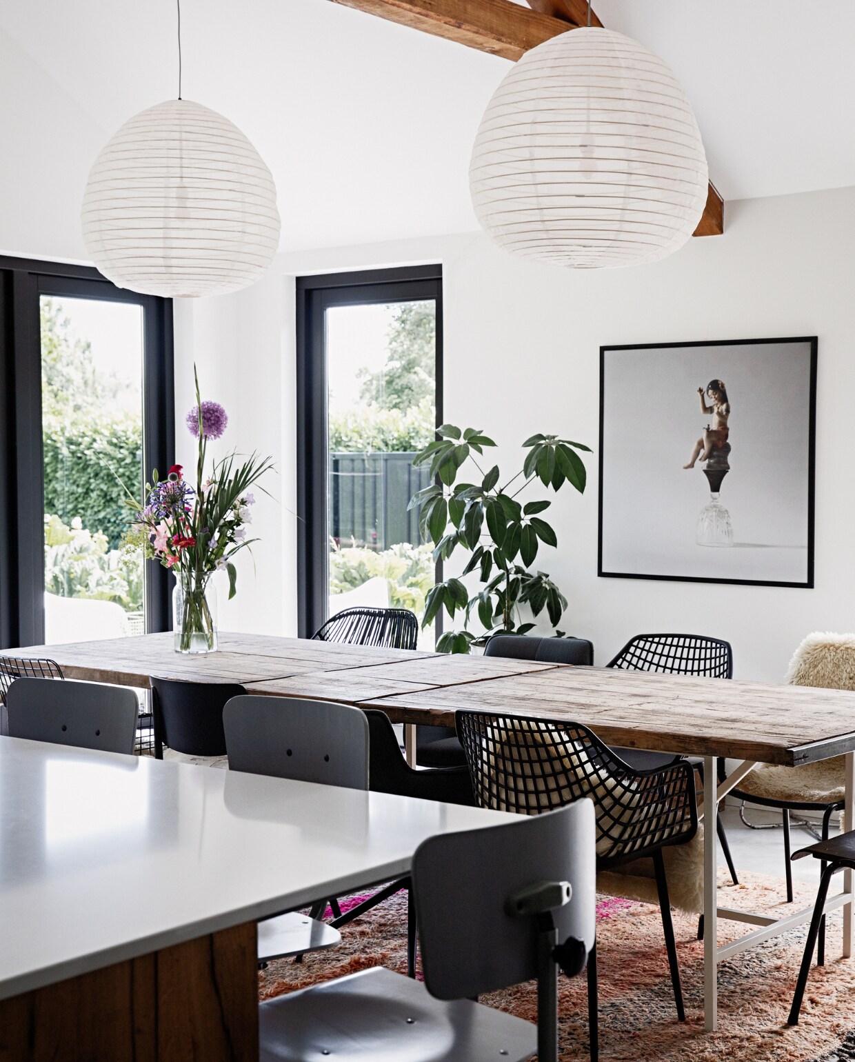 Muurkleur Ral 9016, kleur kozijnen Ral 9005, vloer gevlinderd beton van Bull beton, aanrechtblad De Keukenbladenfabriek, barstoelen De Machinekamer, tafel oude steenschotten op een op maat gemaakte stalen onderstel Gillissen Ontwerp. Stoelen (v.l.n.r. deze kant) draadstoel HKliving, schoolstoel Burbri Antiek, kuipstoel Kwantum, stoffen draaistoel Loods 5, (v.l.n.r. andere kant) zwarte rotan stoel en stoffen draaistoel Loods 5, kuipstoel Kwantum, schoolstoel Burbri met schapenvacht Ikea. Plant gekregen, glazen vaas Bloomon, foto Sake Elzinga, kleed handgemaakt Loods 5. Hanglampen onbekend.