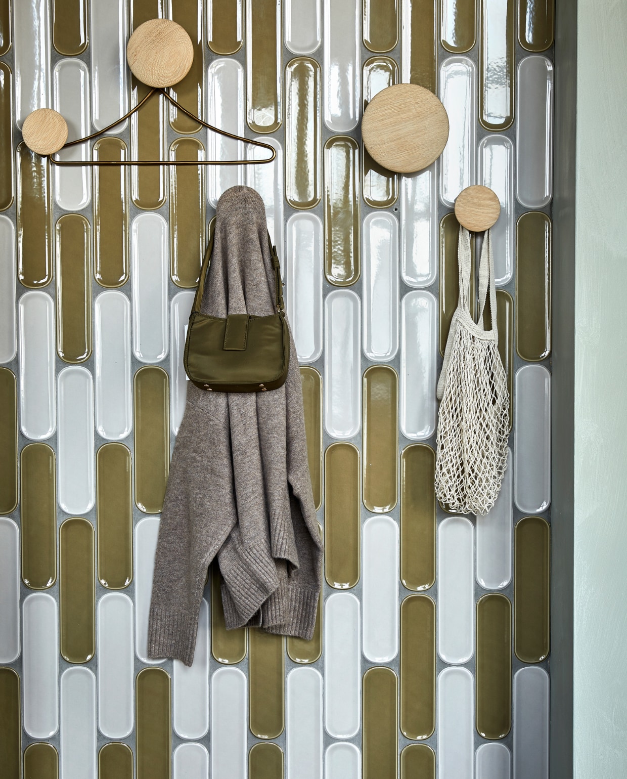 Wandtegels Shapes Greige Round glans, 7,5x30 cm per m² € 68,99,  wandtegels Shapes Olive Round glans, 7,5x30 cm per m² € 68,99. M.m.v. vtwonen.be (wandhaken van Muuto), zarahome.com (messing kledinghanger), zara.com (tas, hoed). Overig privébezit. vtwonen 02 2023 | productie Tanja Saarberg | styling Sanne Ketelaar | fotografie Peggy Janssen