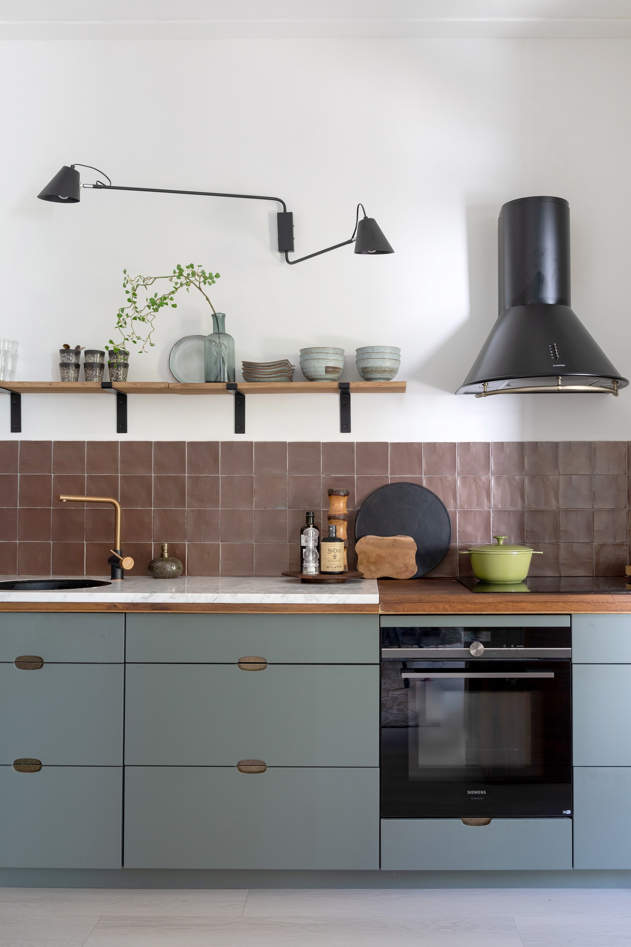 (Binnenkijker) Keuken Kvik, aanrechtblad en wandplanken zelfgemaakt, tegels Tegeldump, kraan Pyramis, zeepdispenser Bijenkorf, wandlamp Qazqa, koelkast Smeg, mokken HKliving, fles en bord Intratuin, borden en kommen Tokyo Design, afzuigkap Klarstein, pan Le Creuset, snijplanken Dille &amp; Kamille, zwart dienblad H&amp;m, houten decoratie kringloop. styling: Sharon Roest | fotografie: Caroline Martinot | tekst: Eveline Stoel
