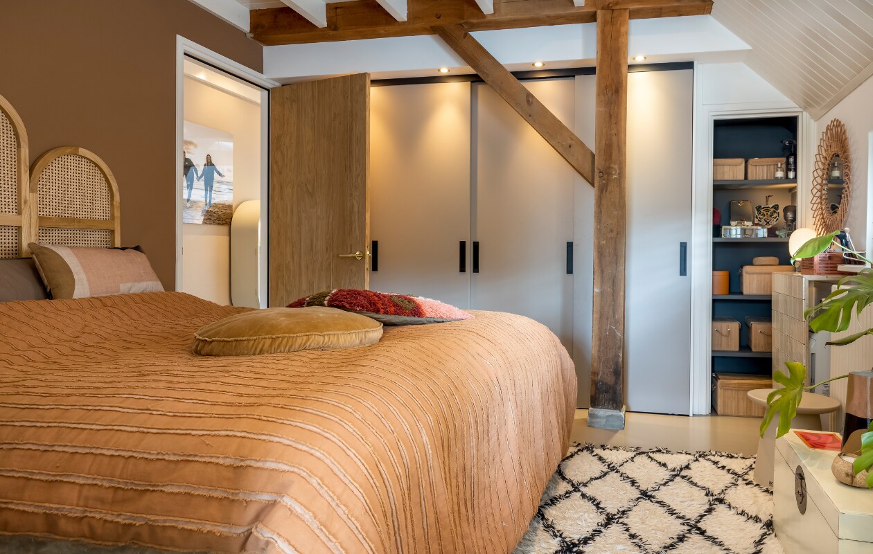 Muurverf Book Room Red van Farrow &amp; Ball, verf plafond RAL 9010. Bed Slaaphof. Hoofdbord, sprei en kussens op bed HKliving. Kastenwand op maat gemaakt. Verf in kast Zwart Mat van Painting The Past. Opbergmanden in kast Xenos, spiegel in kast Sissy-Boy, tijgerkop Doing Goods, lampje Ikea. Rotan spiegel Kwantum. Betegelde kast zelfgemaakt door buurman. Roze mandje Hema. Vloerkleed HKliving. Overig onbekend. vtwonen 2-2023 | styling Karin van Schie | fotografie Henny van Belkom | tekst Saskia Borst