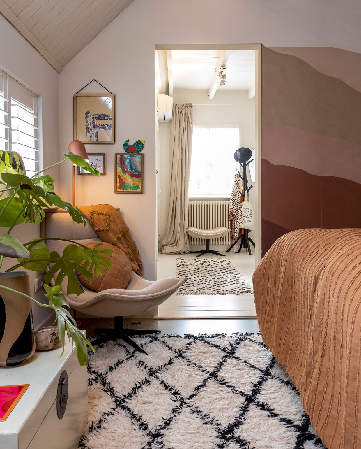 Behang Karwei. Verf plafond RAL 9010. Draaifauteuil Reeva van Bodilson, kussen op fauteuil Bodilson. Lamp achter fauteuil It’s About Romi. Kunstwerken aan muur gemaakt door de kinderen. Vloerkleed kleedkamer HKliving. Gordijn Loft. Ochtendjas Love Stories. Tas aan kapstok Sukha. Hoed Ibiza. Spiegel Sissy-Boy. Overig onbekend. vtwonen 02-2023 | styling Karin van Schie | fotografie Henny van Belkom