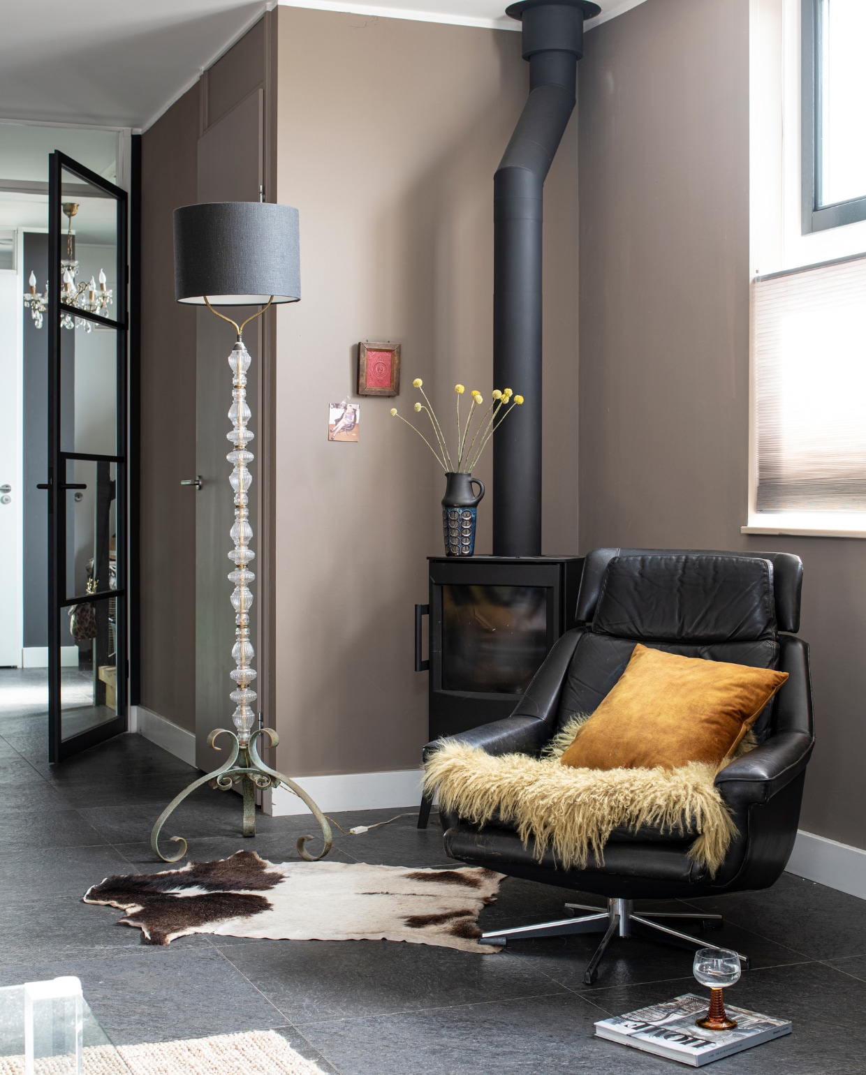 Muurverf Brave Groud van Flexa, taatsdeur Gewoon Gers, schemerlamp antiekmarkt, leren fauteuil erfstuk, kussen kwantum, vacht Leen Bakker, houtkachel Wiking Mini 2, wijnglas Tablejoy, plisségordijnen Veneta, vaas kringloop. Overig onbekend. vtwonen 01-2023 | Productie Inside Homepage | Fotografie Louis Lemaire | Styling Anja Bas Backer