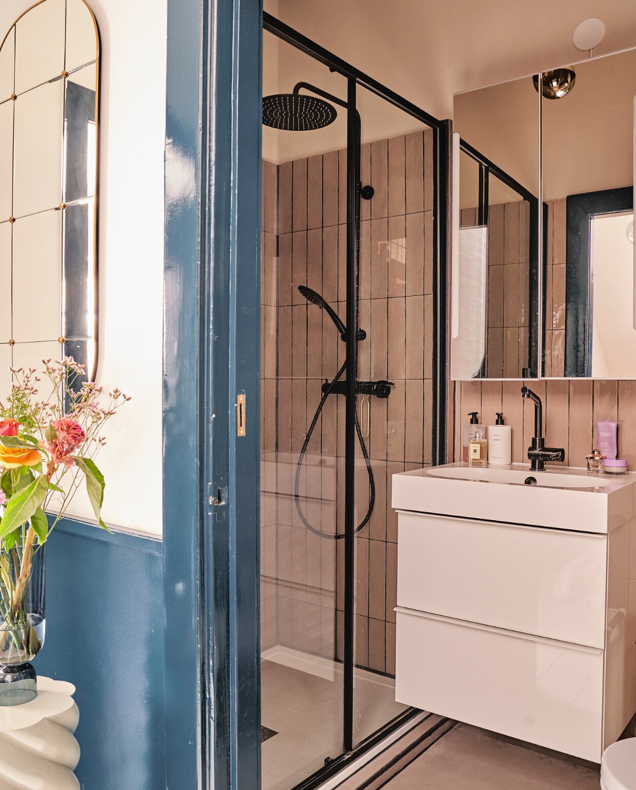Witte pilaar &amp;klevering, vaas Hay, spiegel Zara Home, badkamermeubel en spiegelkast Ikea, douchekop en -kraan Tiger, wandtegels in Latte glans van Tegels in huis, verf deurkozijn Hague Blue van Farrow &amp; Ball. vtwonen 02-2023 | productie CocoFeatures.com | fotografie Muk van Lil | tekst Caroline Westdijk