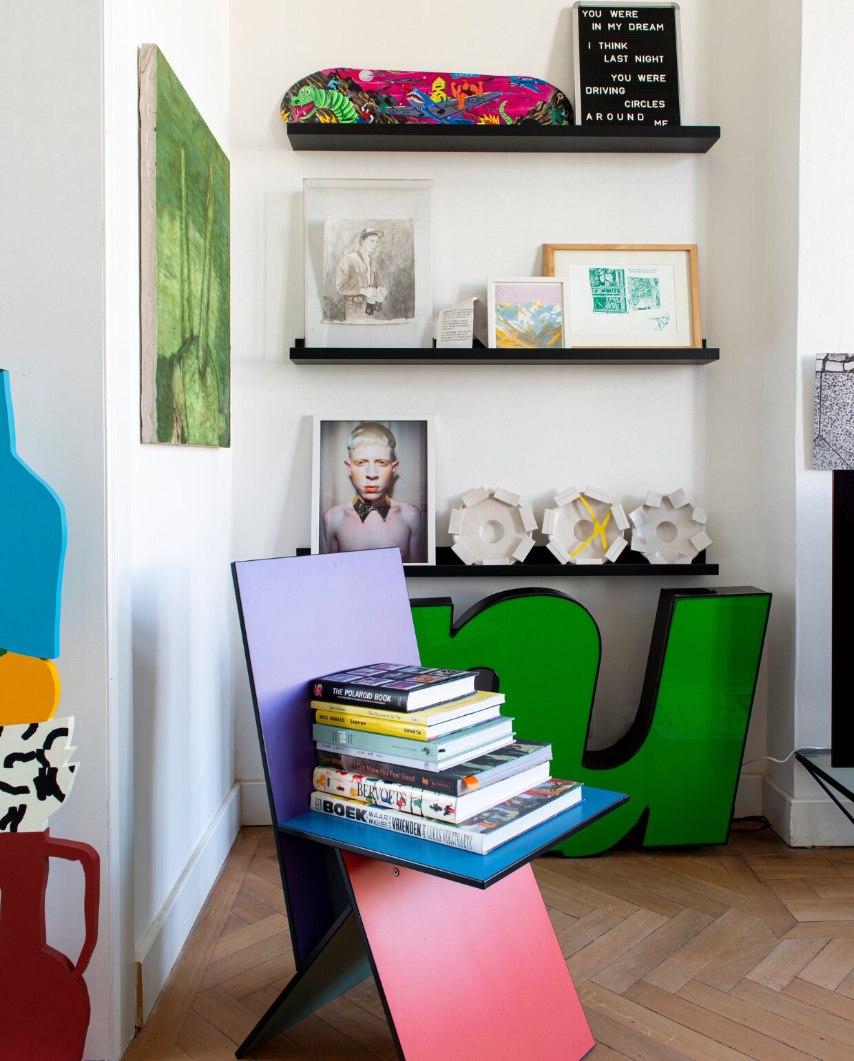 Stoel van Verner Panton voor Ikea, links sculptuur We Are Out of Office, groen schilderij Josse Keppens, skateboard Brecht Vandenbroucke, eronder tekening Ward Zwart, daarnaast tekening Joost Stokhof, eronder aardewerk Carla van Ouwenaller, daarnaast foto Ignacio Trias. Planken Ikea, letters Instagram, overig onbekend. vtwonen 02-2023 | styling: Jeske Weel | fotografie: Caroline Coehorst
