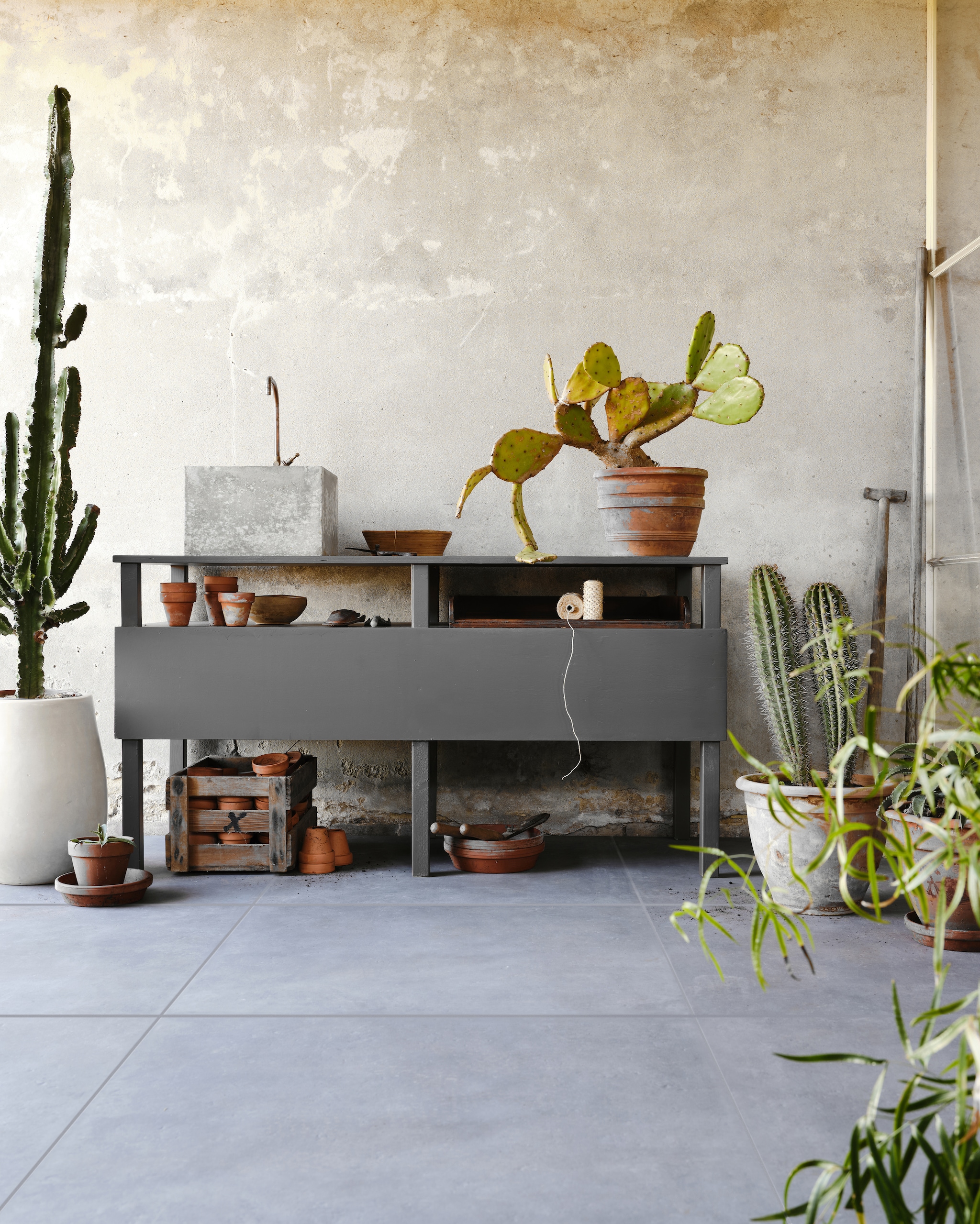 Tuintegel Solostone Mold Basalt van vtwonen, 70x70 cm € 79,95 per m² (ook in de kleuren Taupe en Grit). M.m.v. com-anders.nl (werkbank/buitenkeuken inclusief wasbak en kraan), intratuin (terracotta bloempotten). Overig privébezit. vtwonen 03-2023 | productie Tanja Saarberg | styling Marlies Does | fotografie Bart Brussee