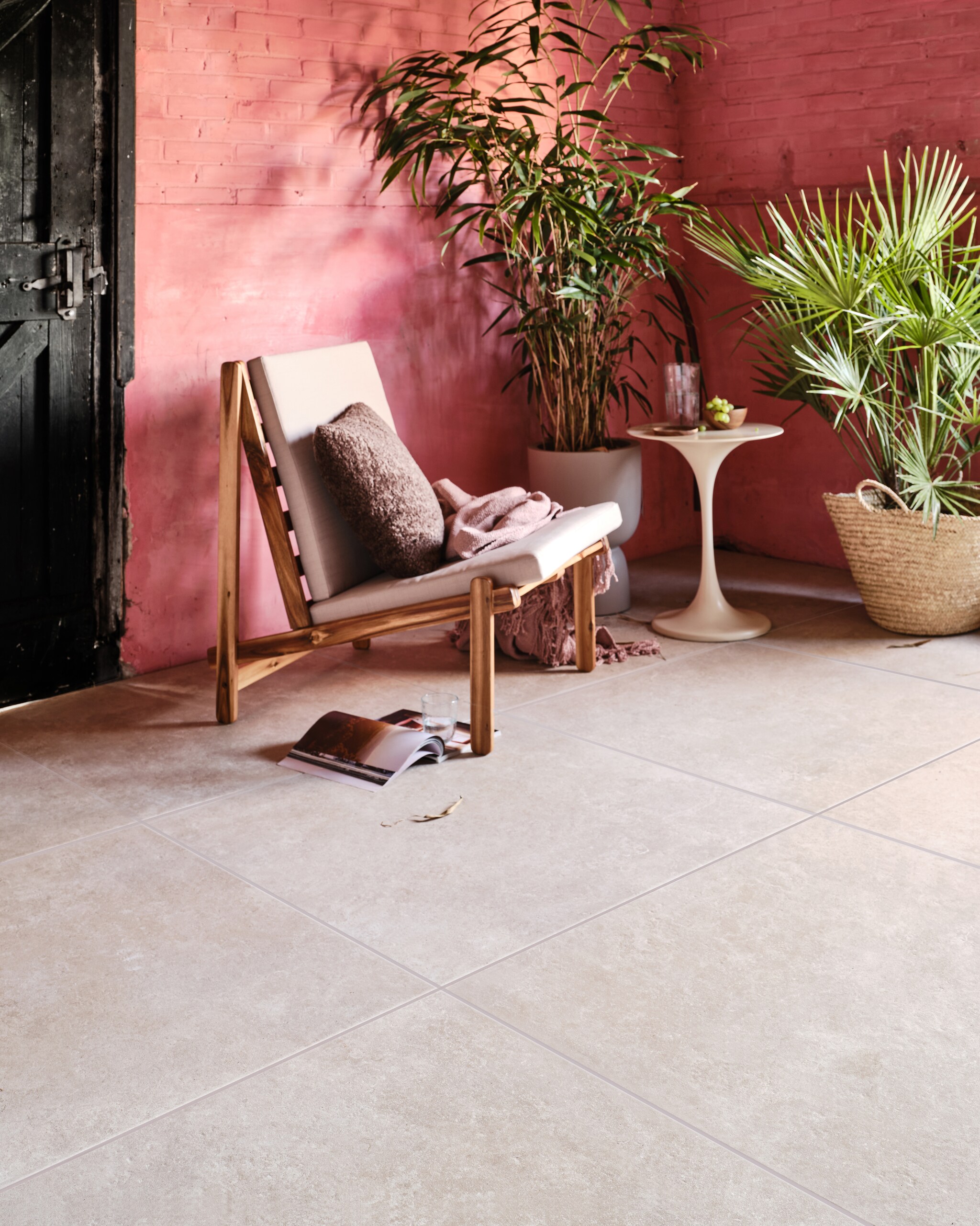 Tuintegel Solostone Unico Sand van vtwonen, 90x90 cm, per m² € 89,50. Ook in de kleur Antracite. vtwonen.be (loungestoel Gani van Bloomingville, kussen vtwonen collectie, plaid van Malagoon, glas en karaf van Serax, bloempot van Elho), householdhardware.nl (bijzettafel, rieten mand), com-anders.nl (houten bakje en schotel). vtwonen 03-2023 | productie Tanja Saarberg | styling Marlies Does | fotografie Bart Brussee
